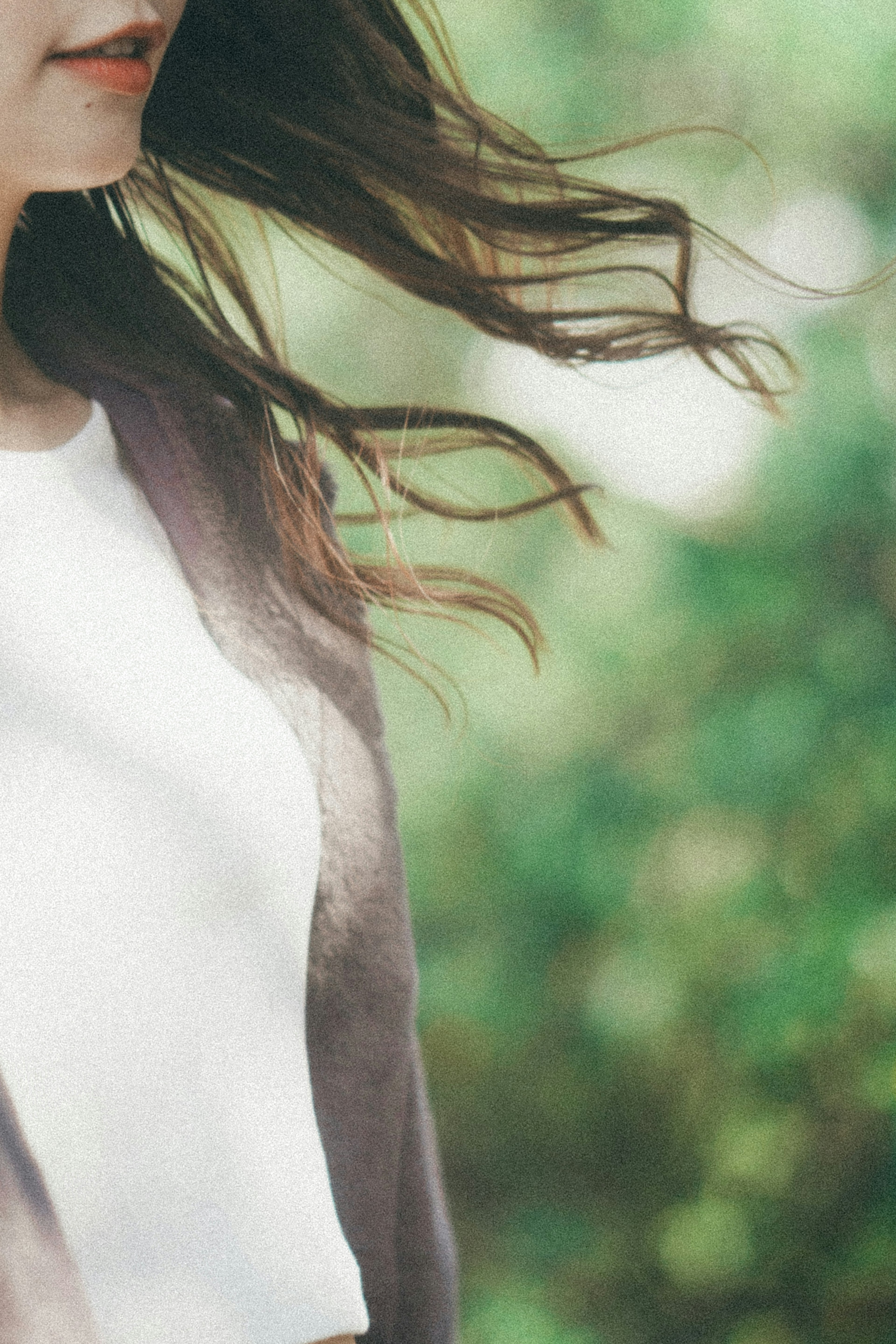 La ropa y el cabello de una mujer ondeando al viento contra un fondo verde