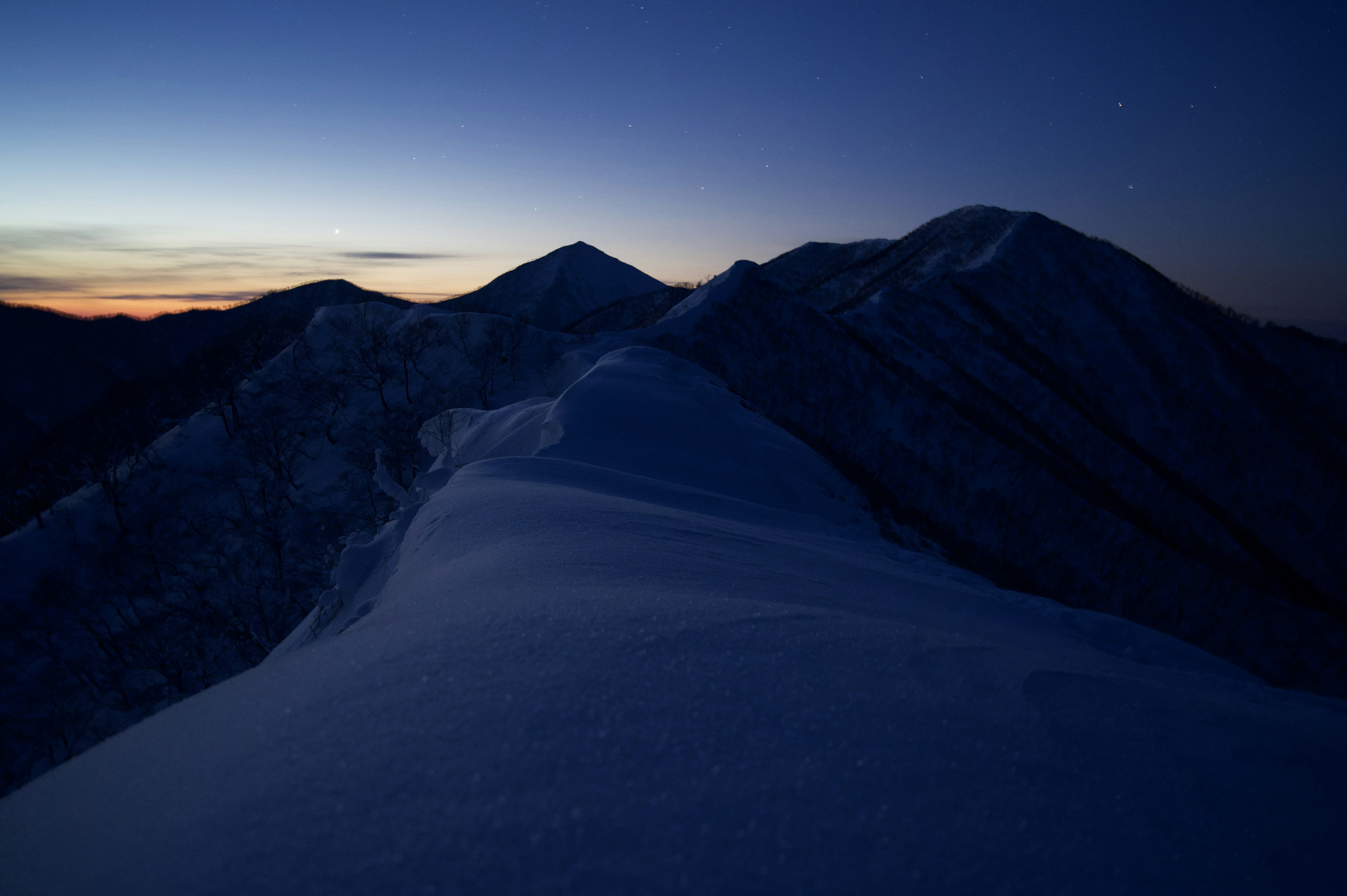 夜明け前の雪に覆われた山々の風景