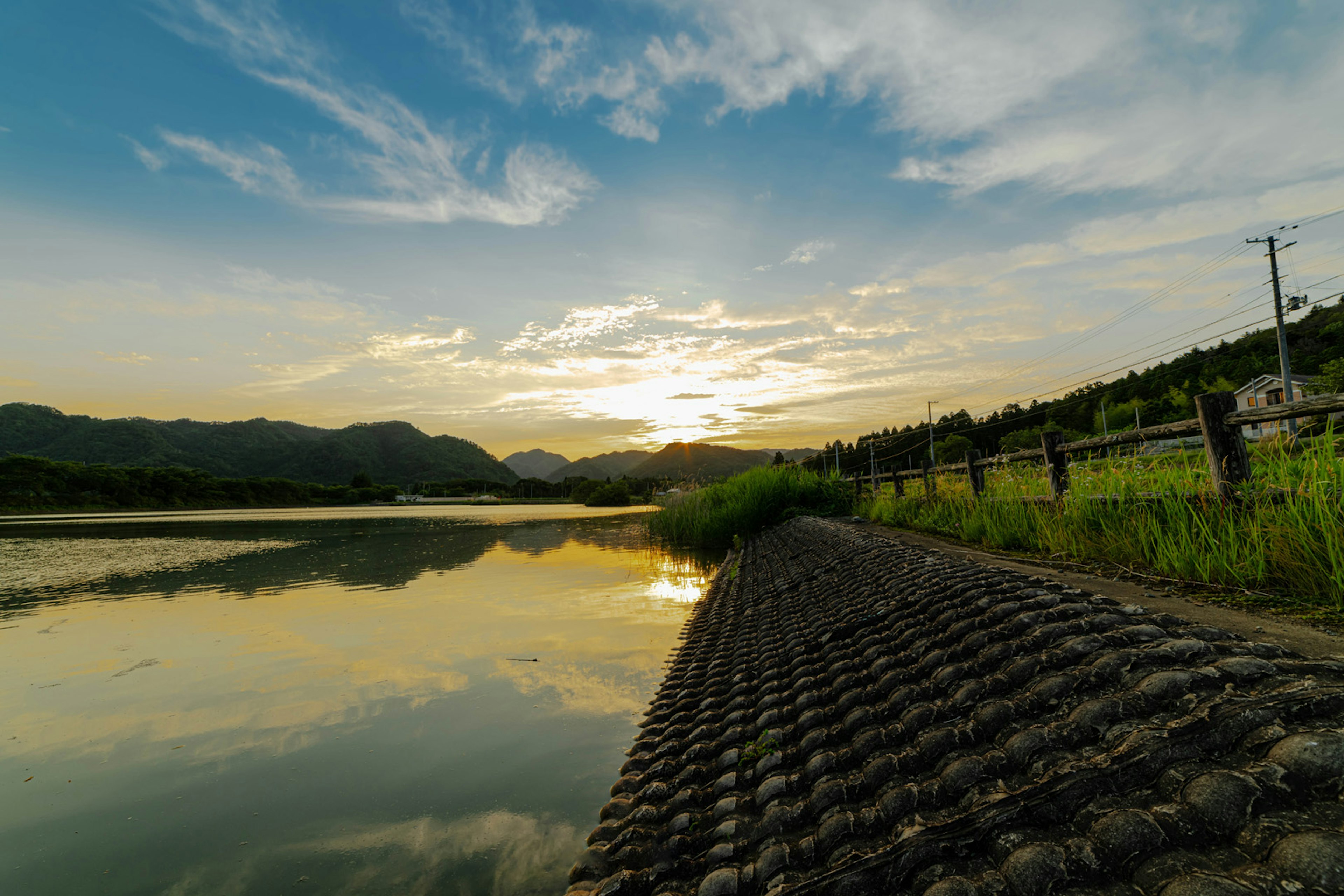 Vue panoramique du coucher de soleil sur une rivière calme avec des montagnes en arrière-plan