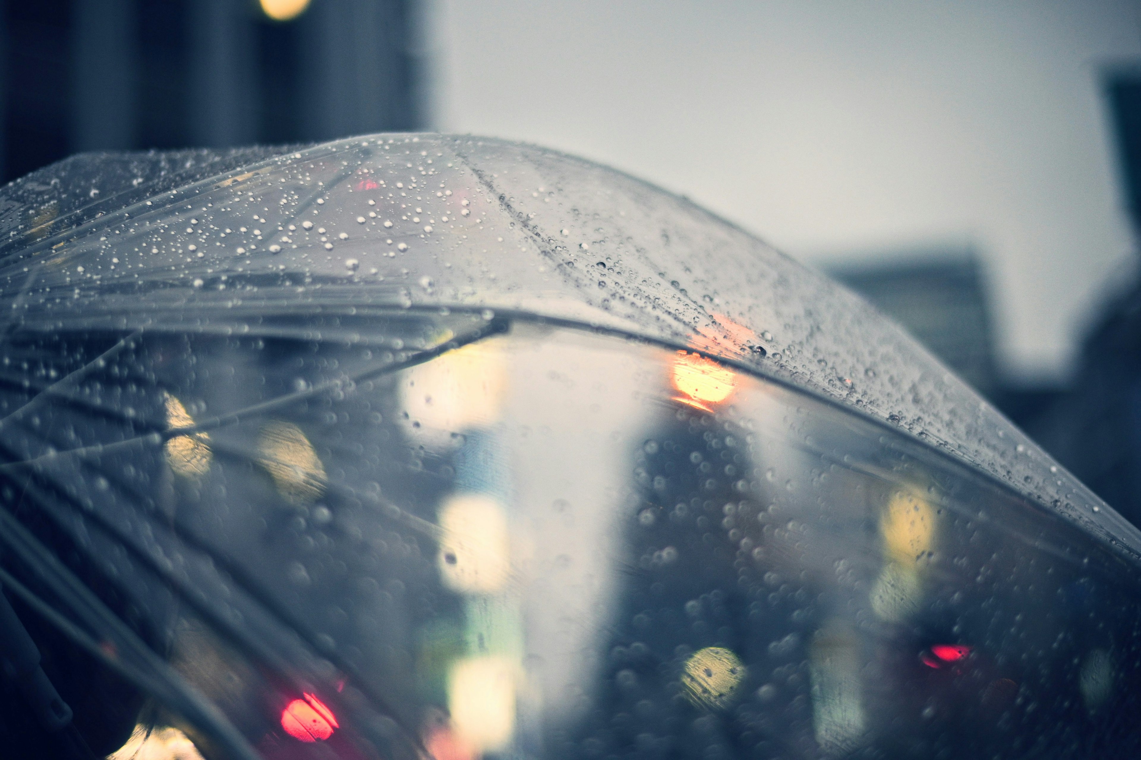 Paraguas transparente bajo la lluvia con luces de ciudad borrosas