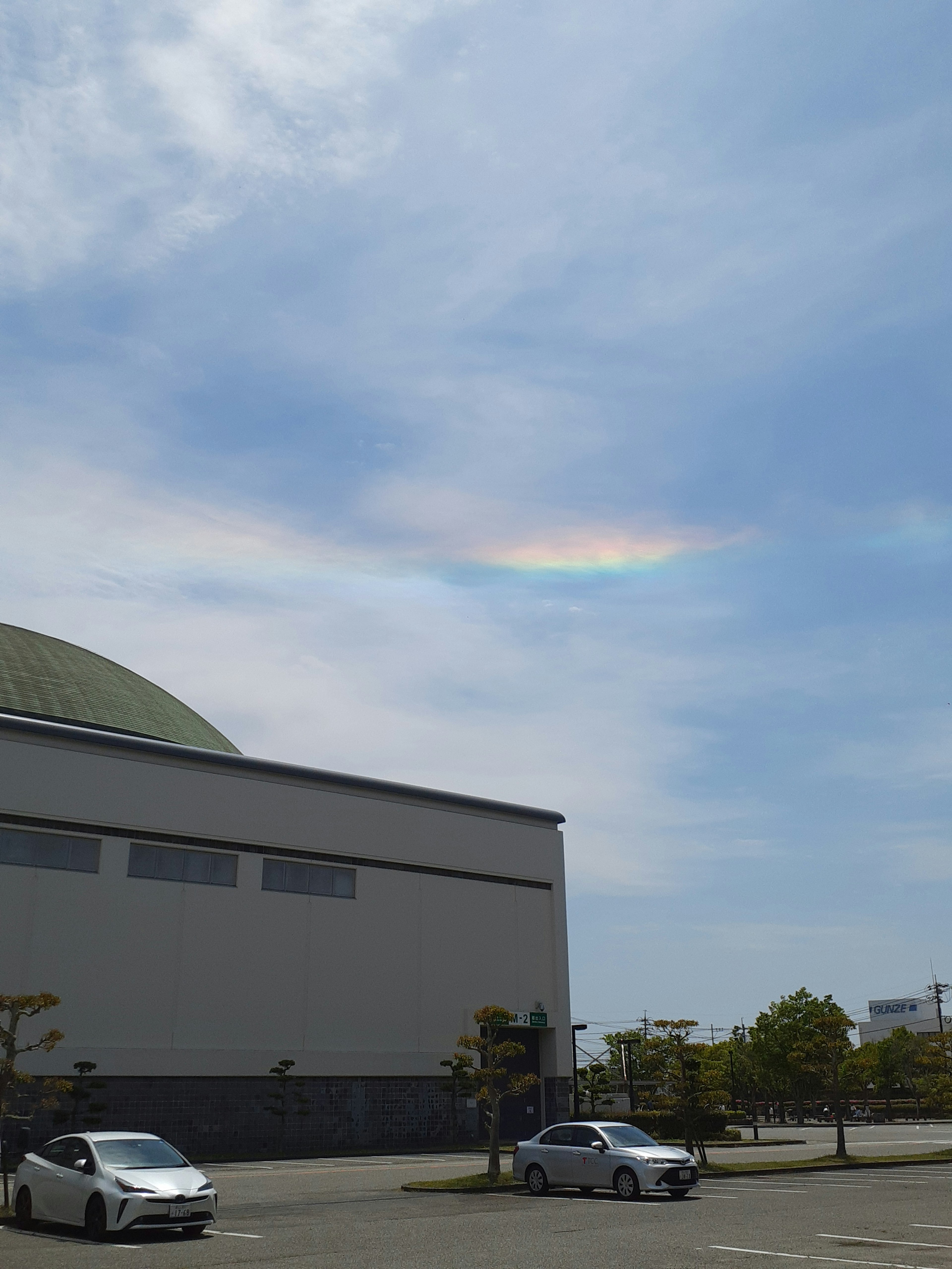 青空に現れた虹のような雲と建物の風景