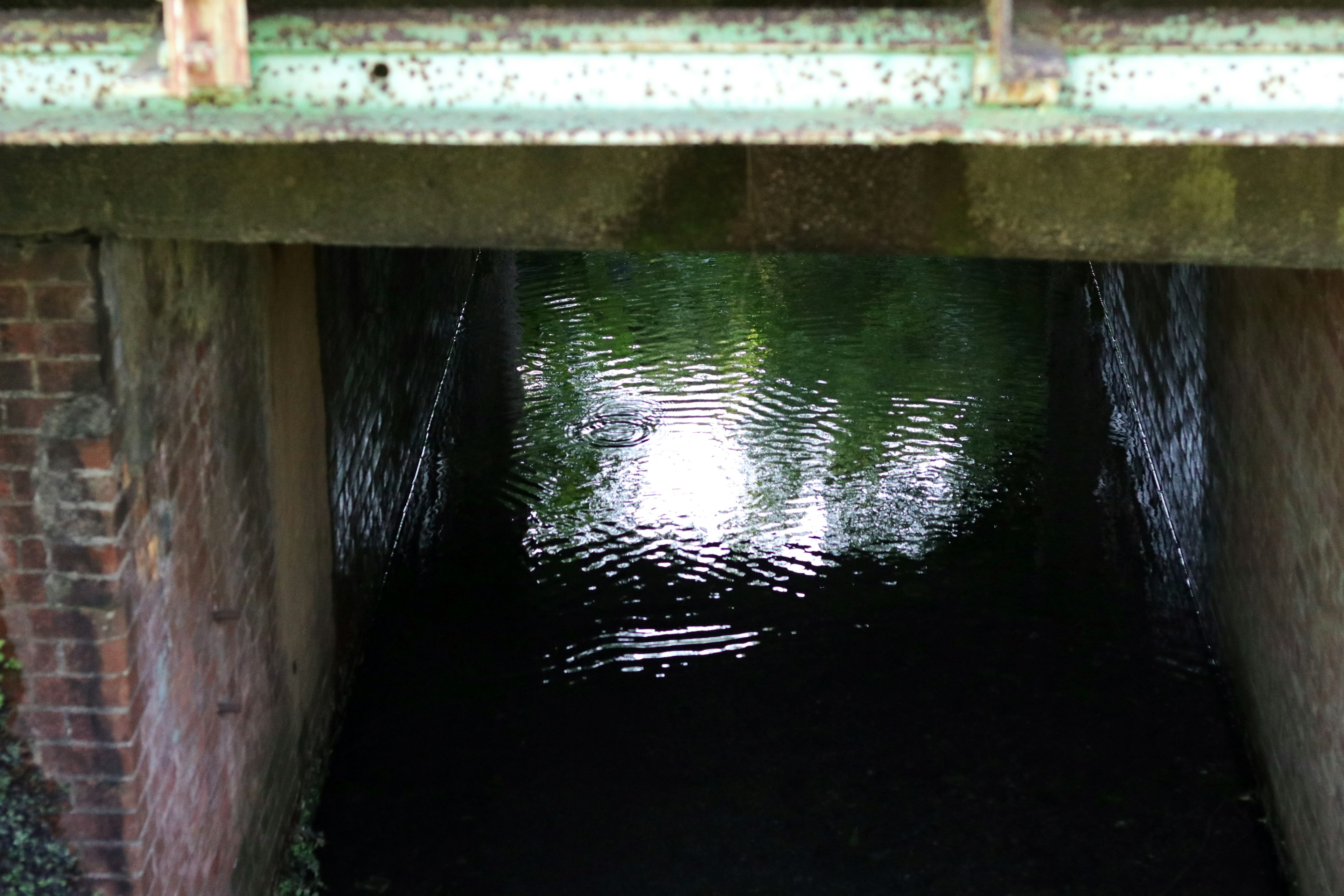 Eingang zu einem dunklen Tunnel mit Wasser, das Licht reflektiert