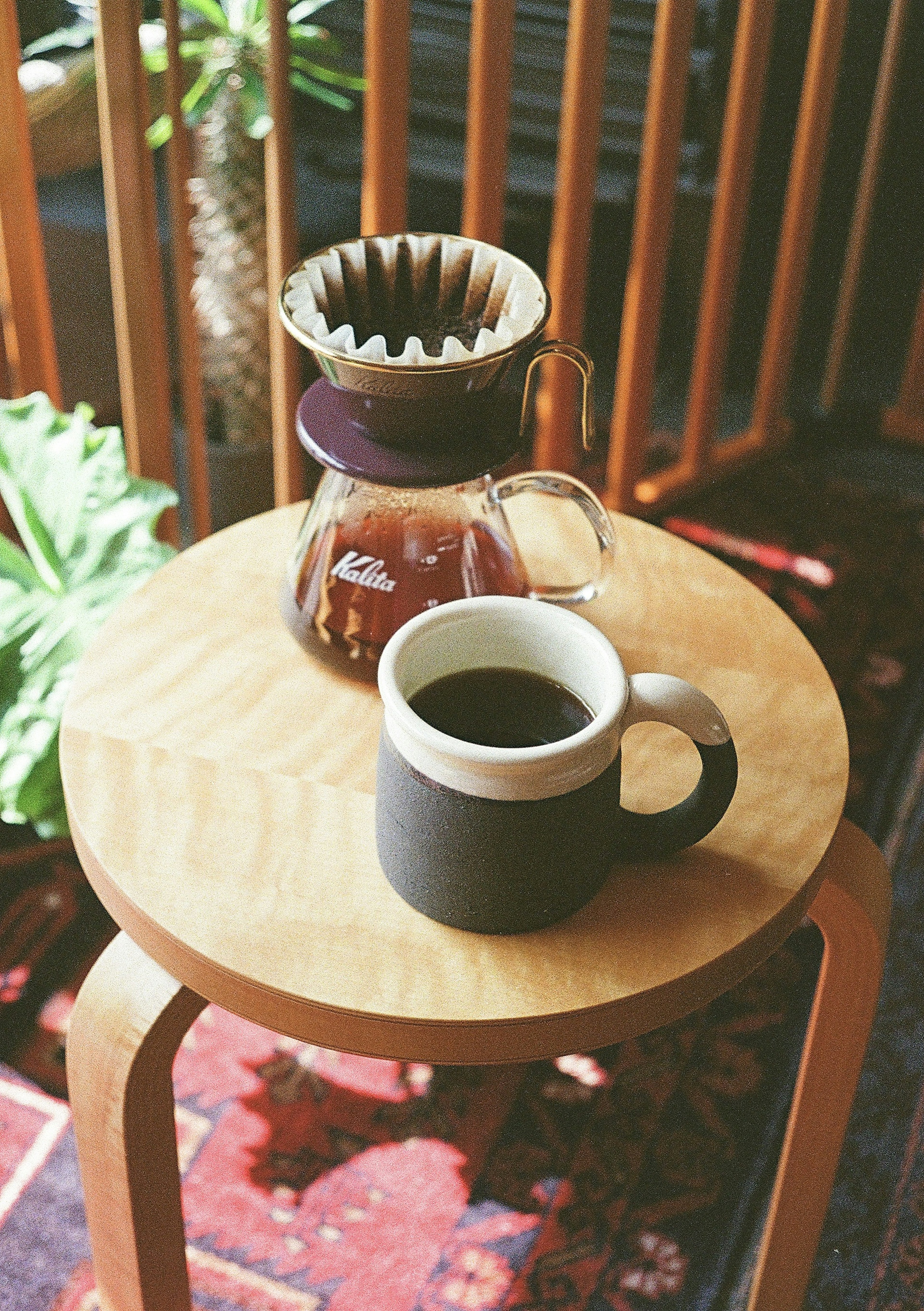 Meja kayu dengan peralatan penyeduhan kopi dan cangkir kopi hitam