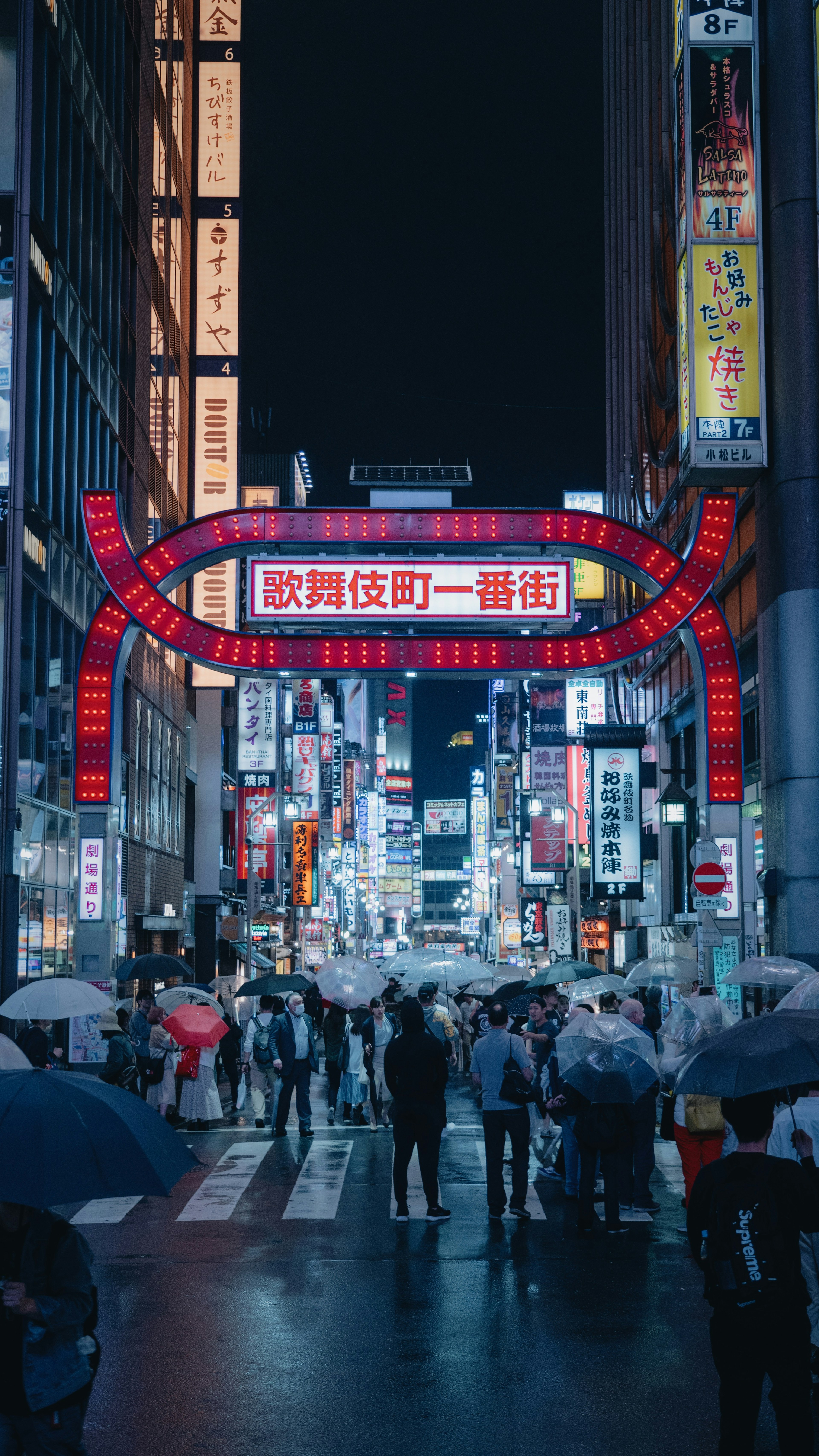 Multitud de personas bajo un brillante letrero de neón en un distrito comercial de Tokio