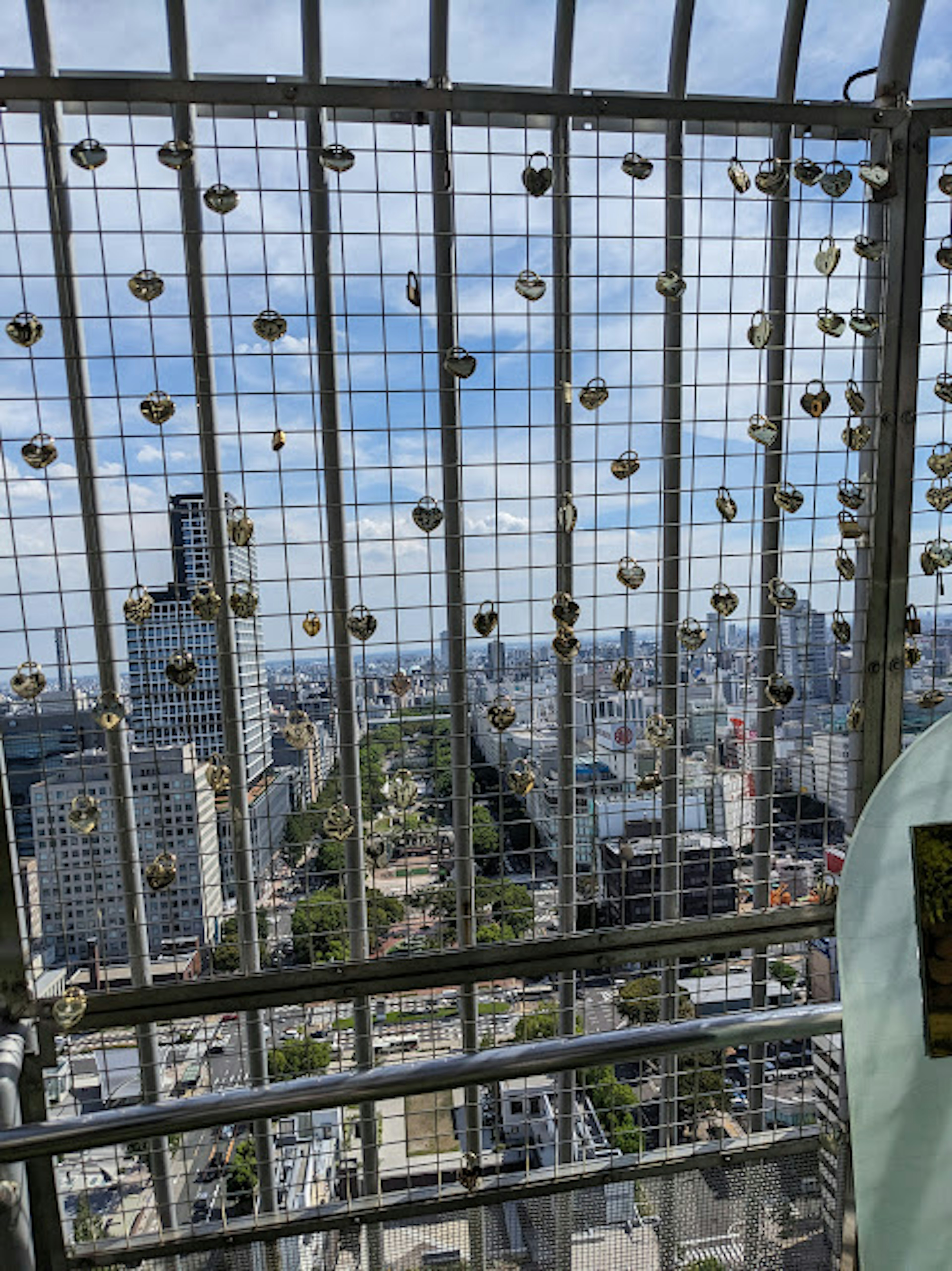 Vista di un paesaggio urbano attraverso una recinzione metallica decorata con numerosi lucchetti d'amore