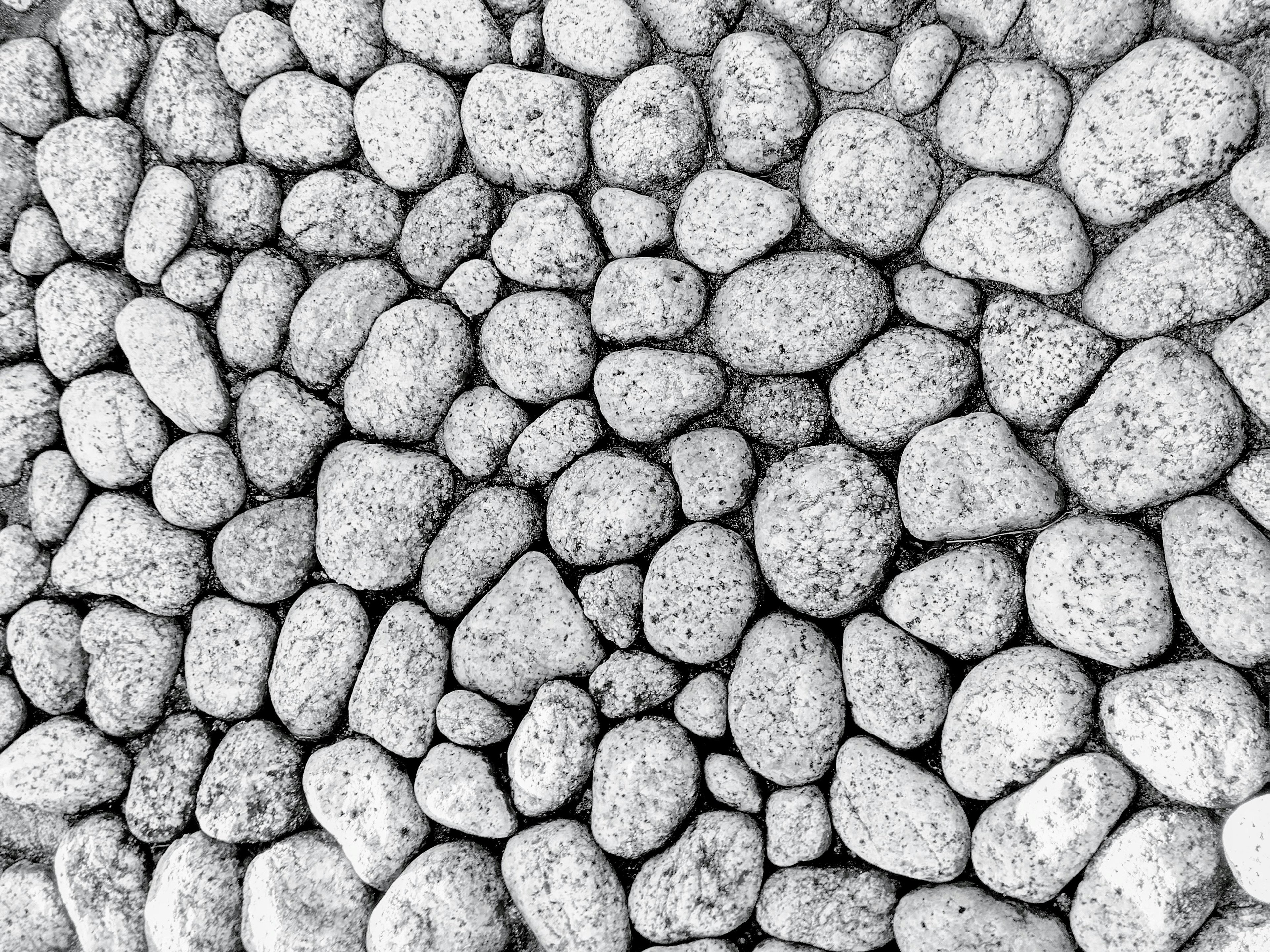 A textured pattern of smooth pebbles in black and white