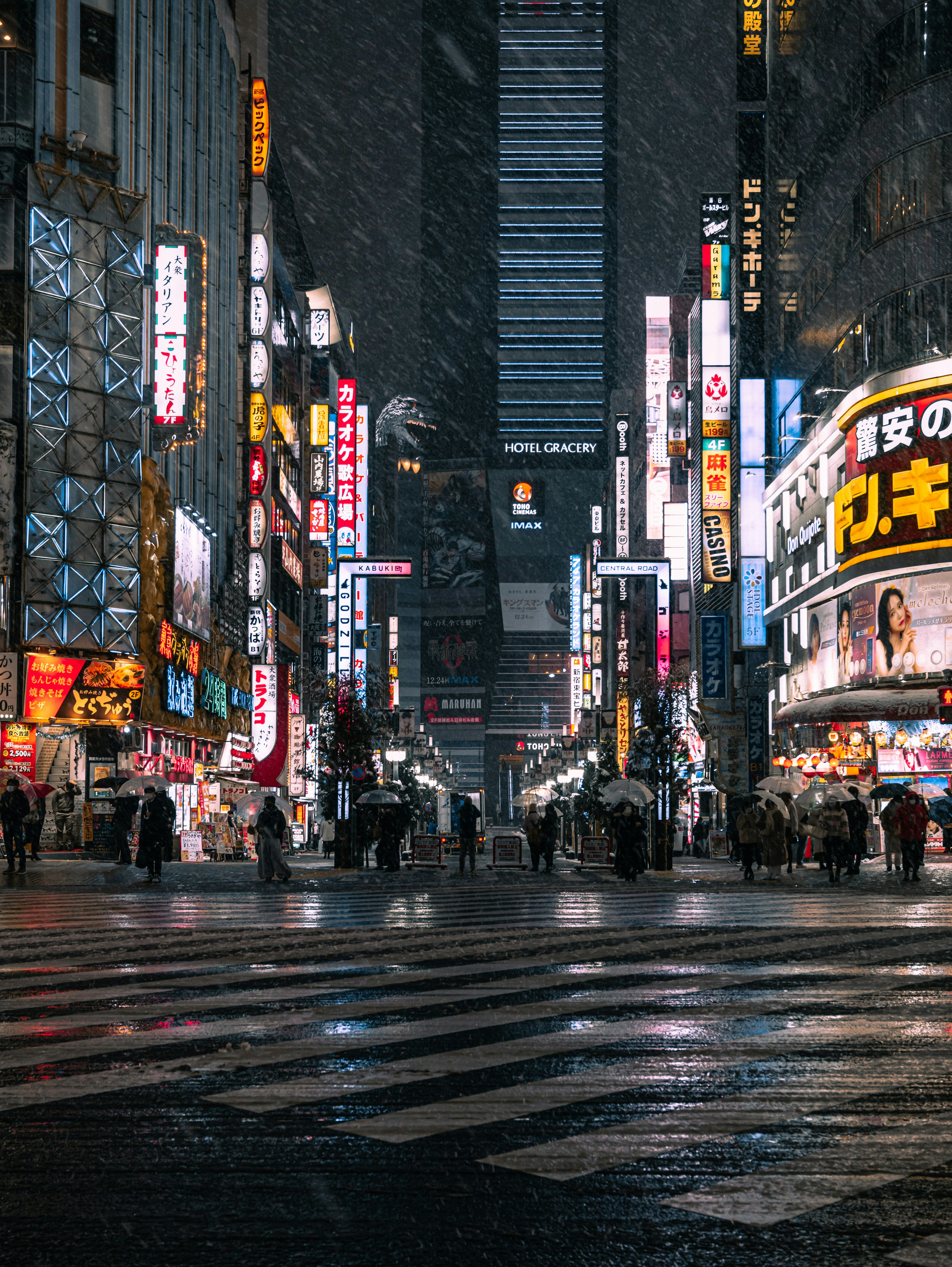 Menschen an einer Kreuzung in Shinjuku an einem verschneiten Abend mit Neonlichtern