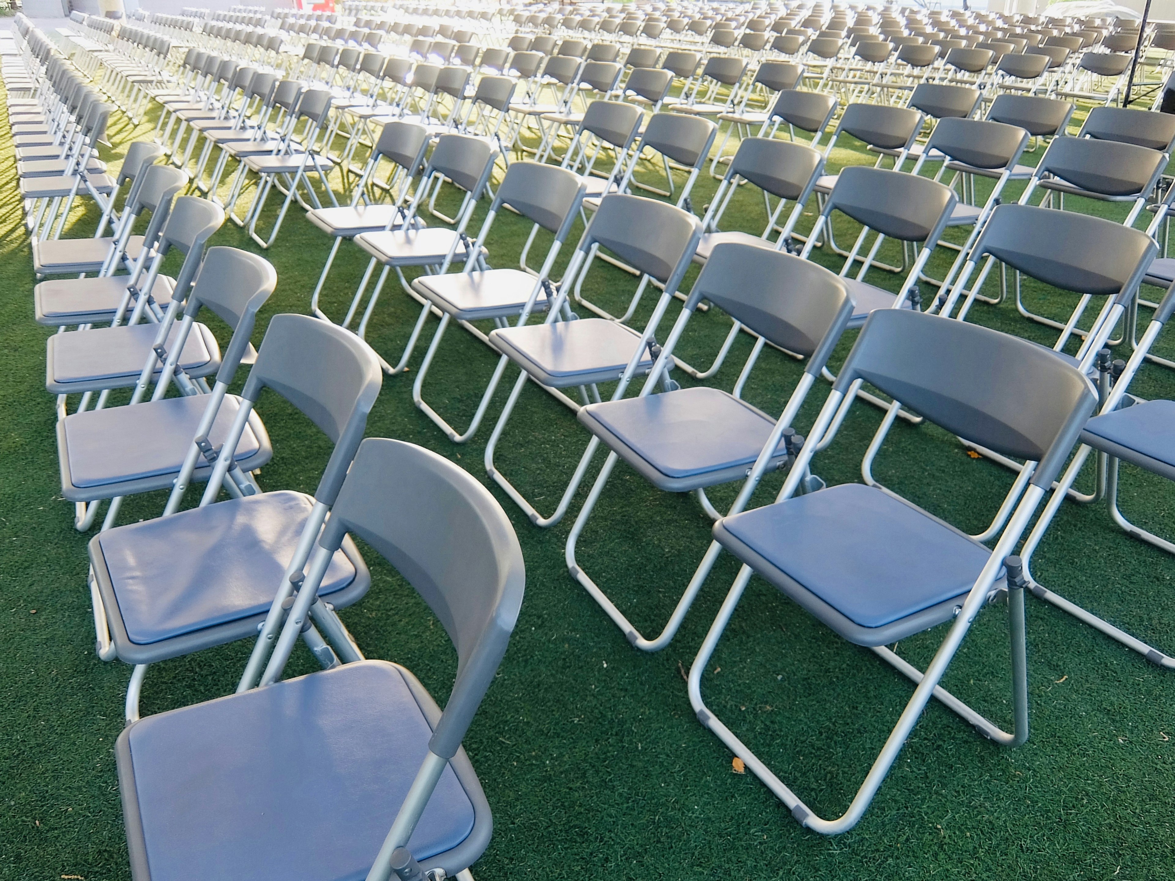 Rows of gray folding chairs arranged on grass