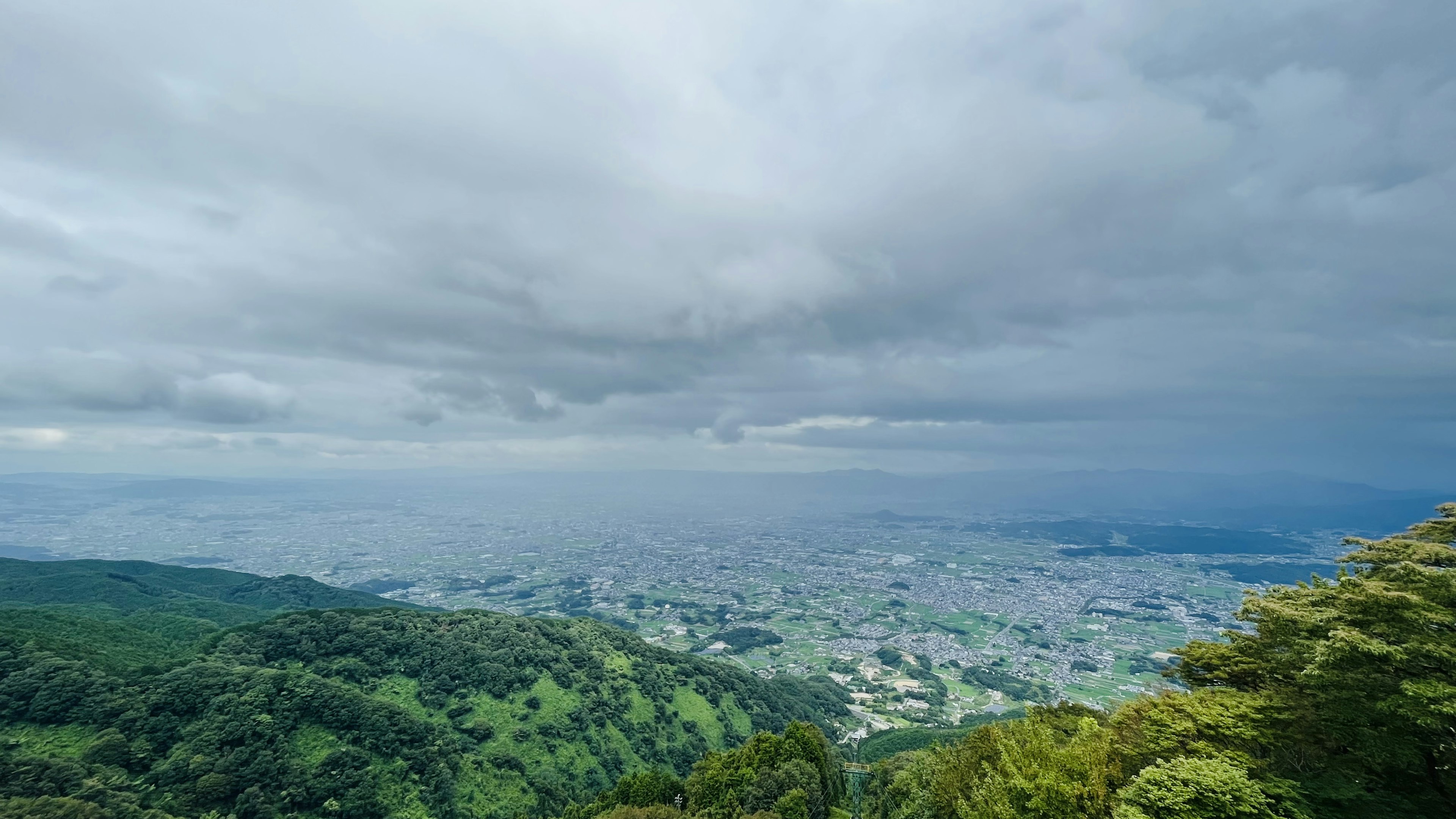 Panoramablick auf grüne Berge und eine weitläufige Stadtlandschaft