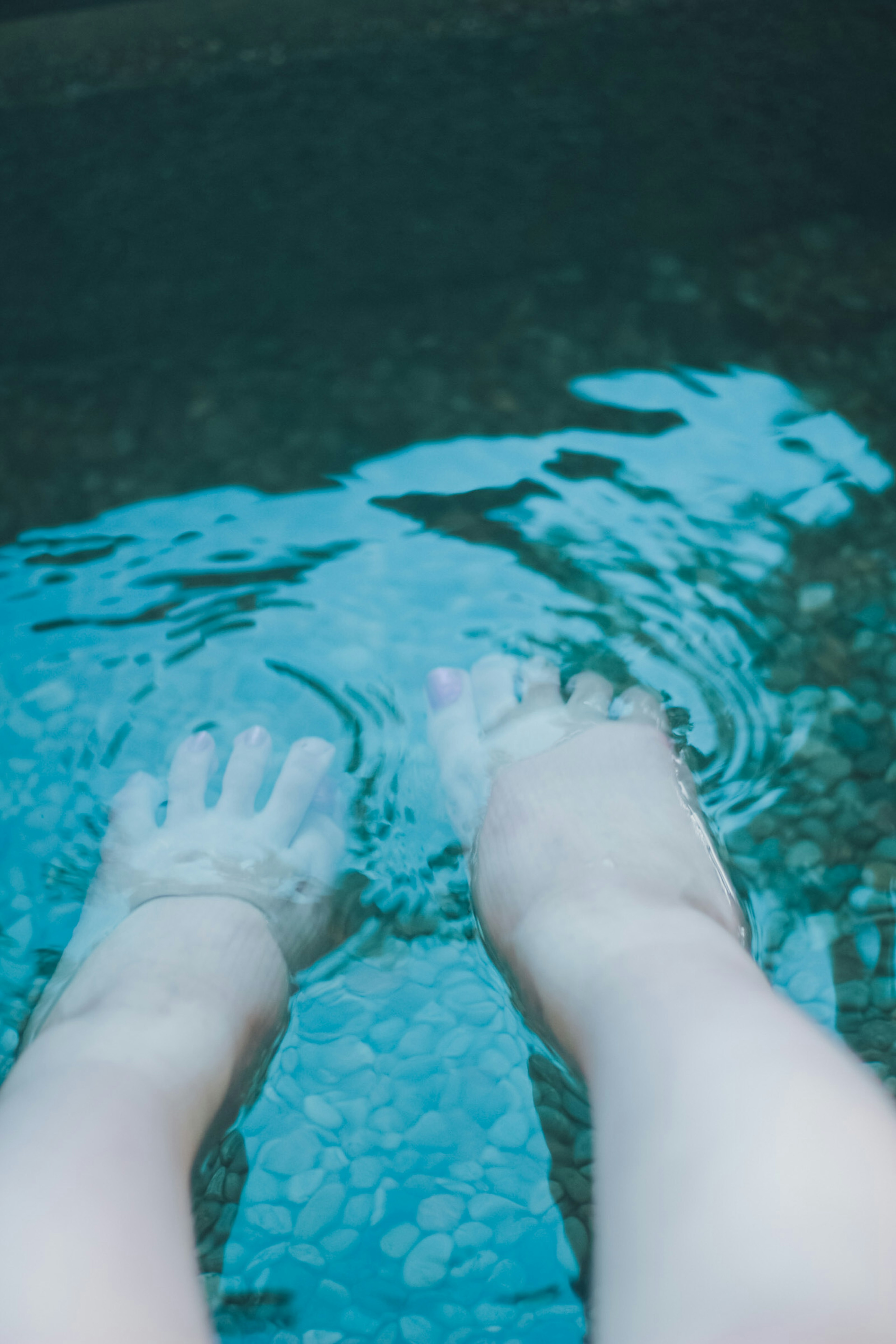 Person's feet submerged in water with ripples