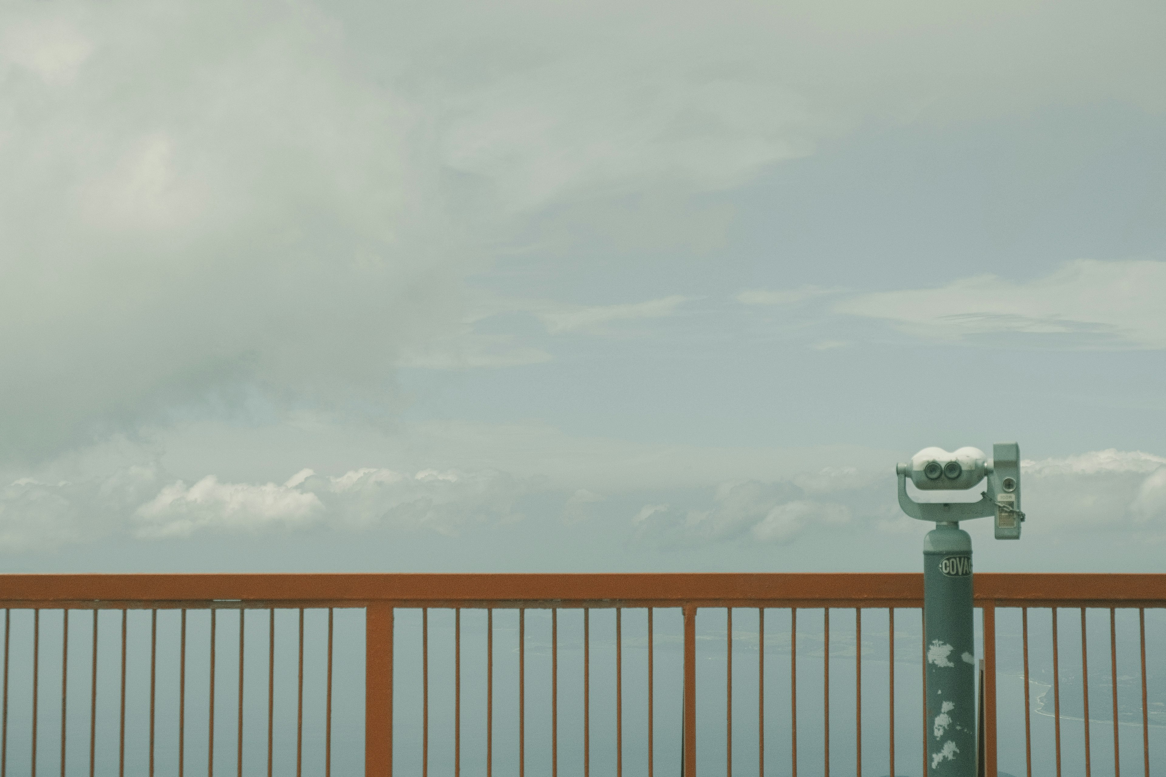 Viewing platform with a telescope overlooking mountains and cloudy sky