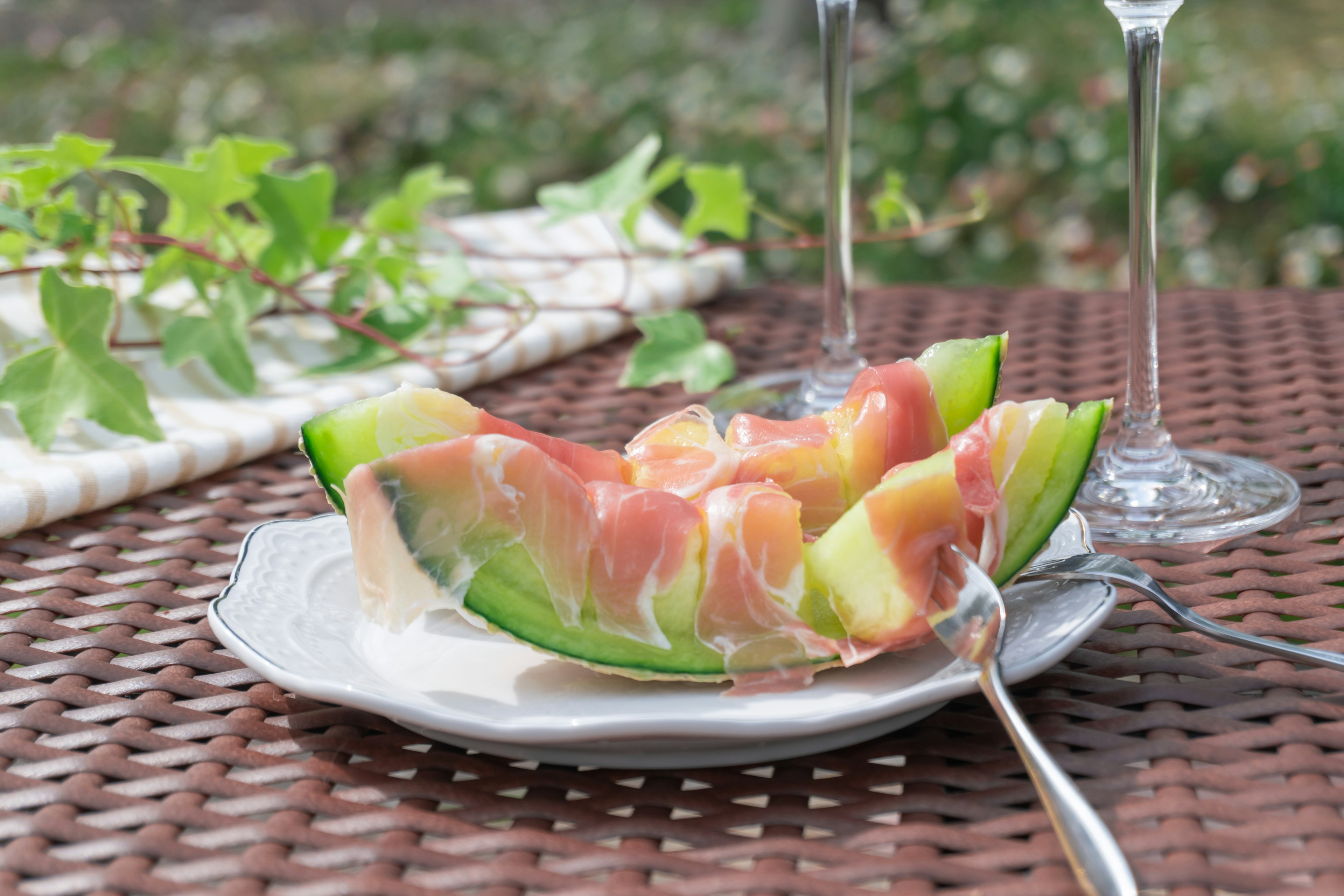 Un plato de rodajas de sandía envueltas en jamón sobre una mesa rústica