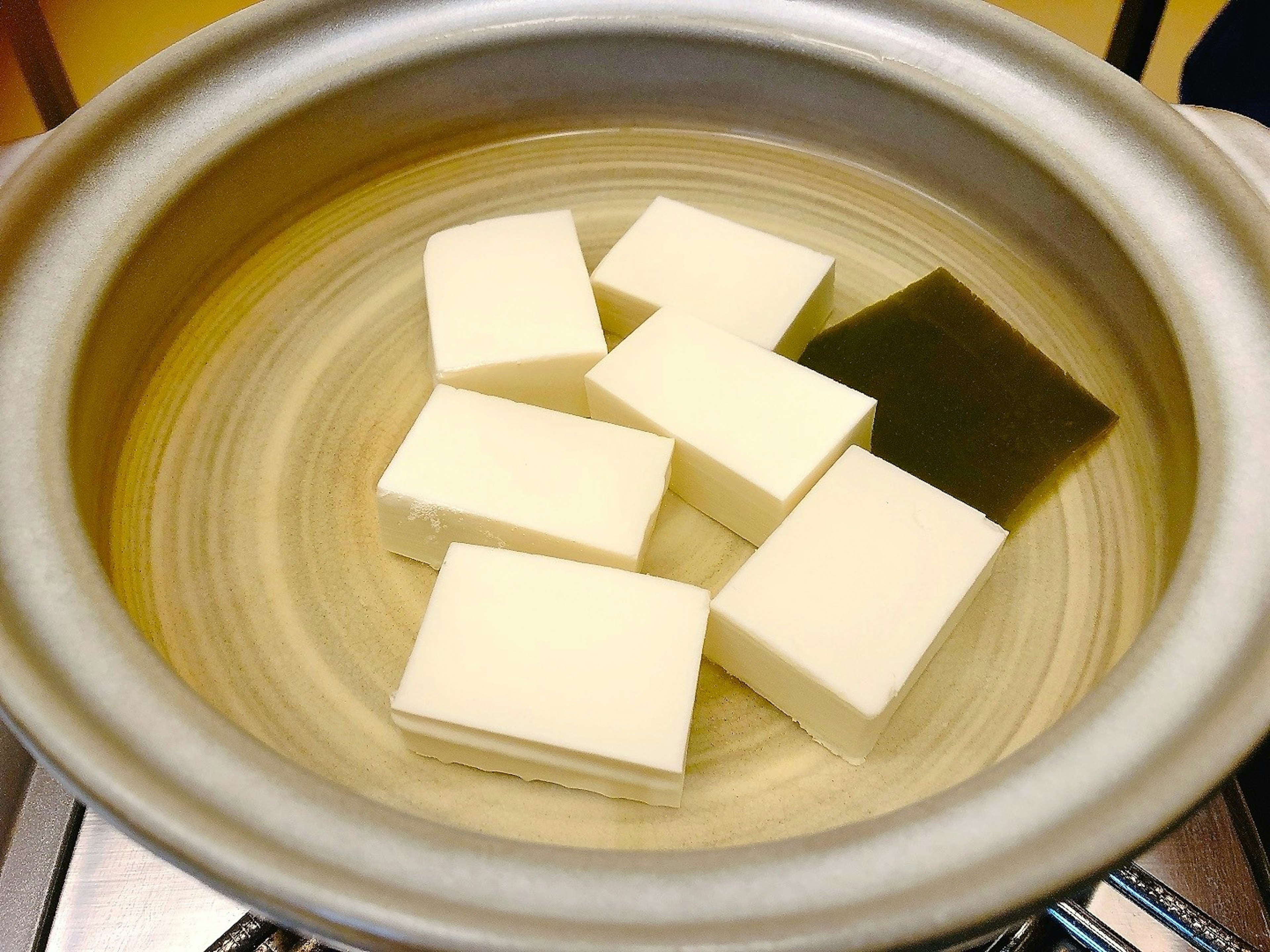 Blocchi di tofu e un pezzo di kombu in una pentola