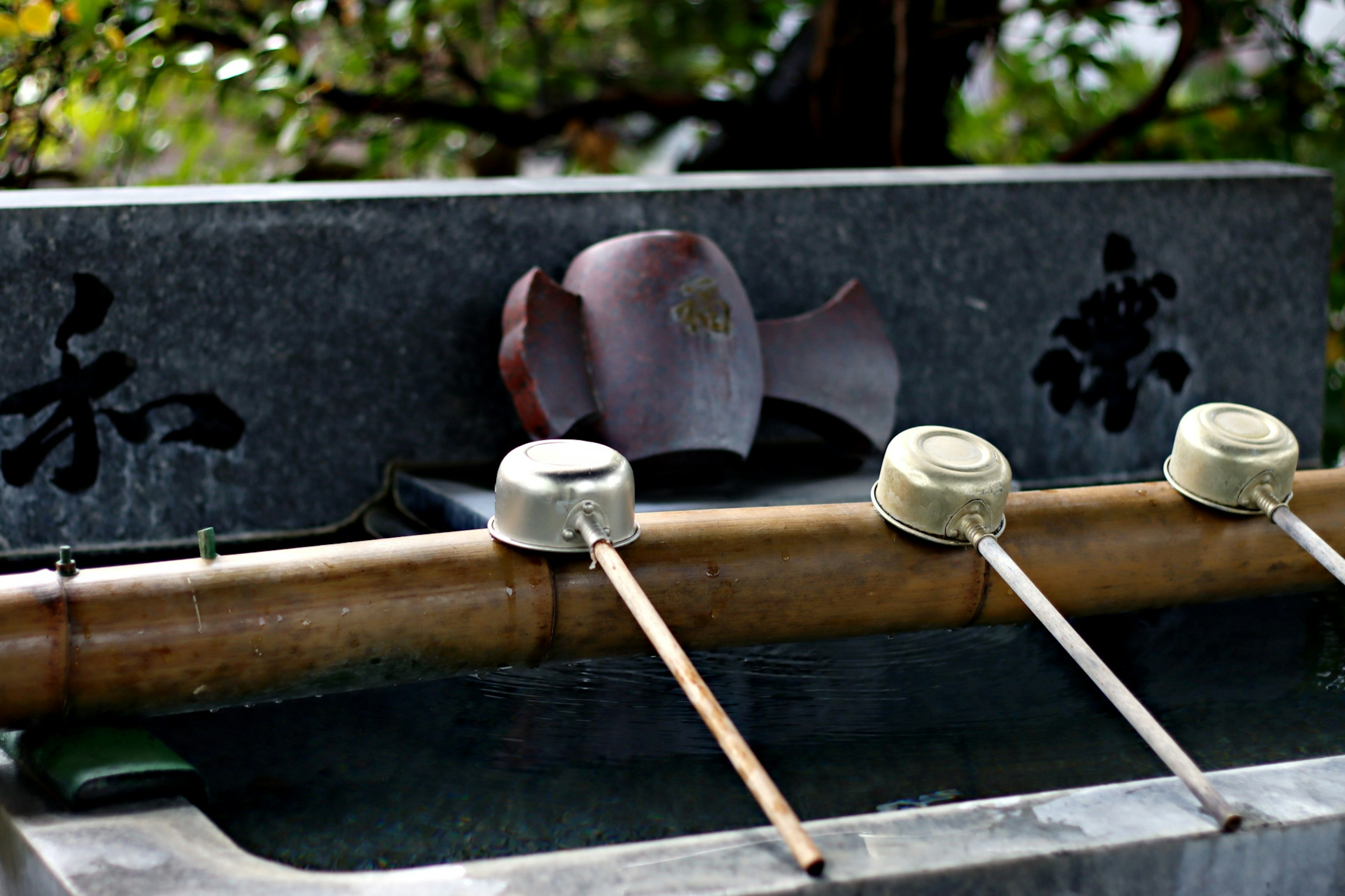 Stone water basin with bamboo ladles and flowing water