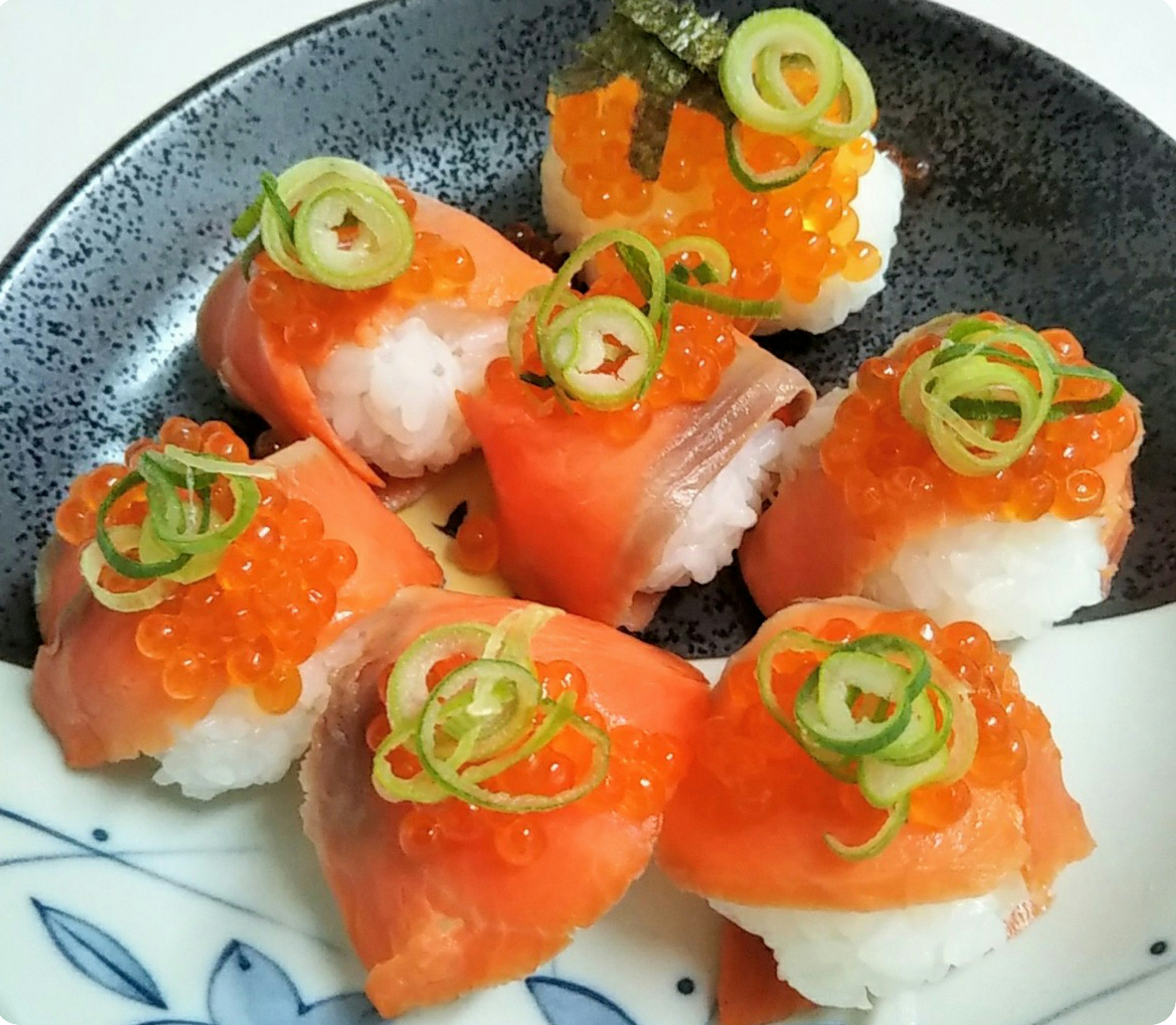 Piring sushi yang dihiasi dengan salmon oranye cerah dan telur ikan