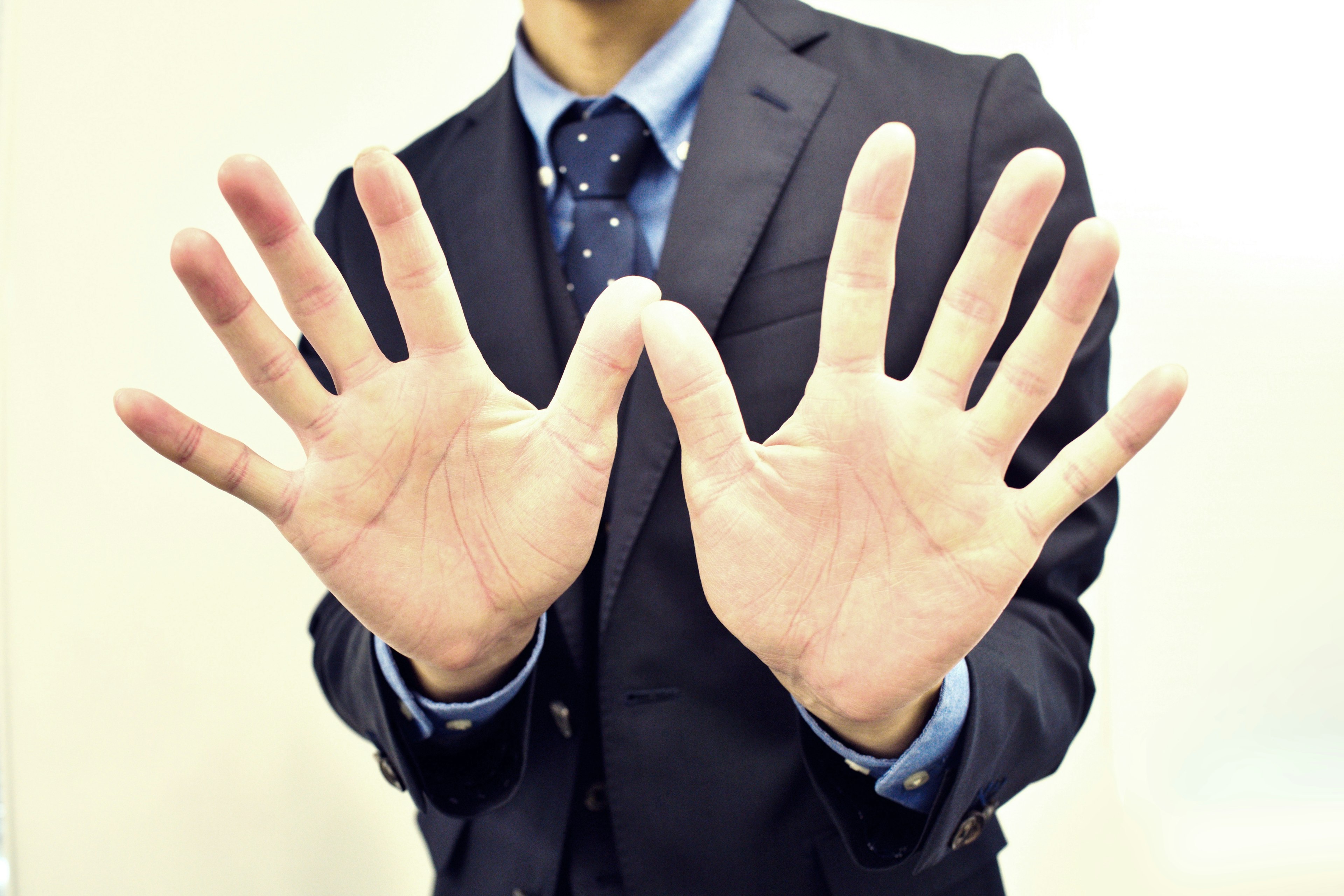 A man in a suit showing both hands with fingers spread