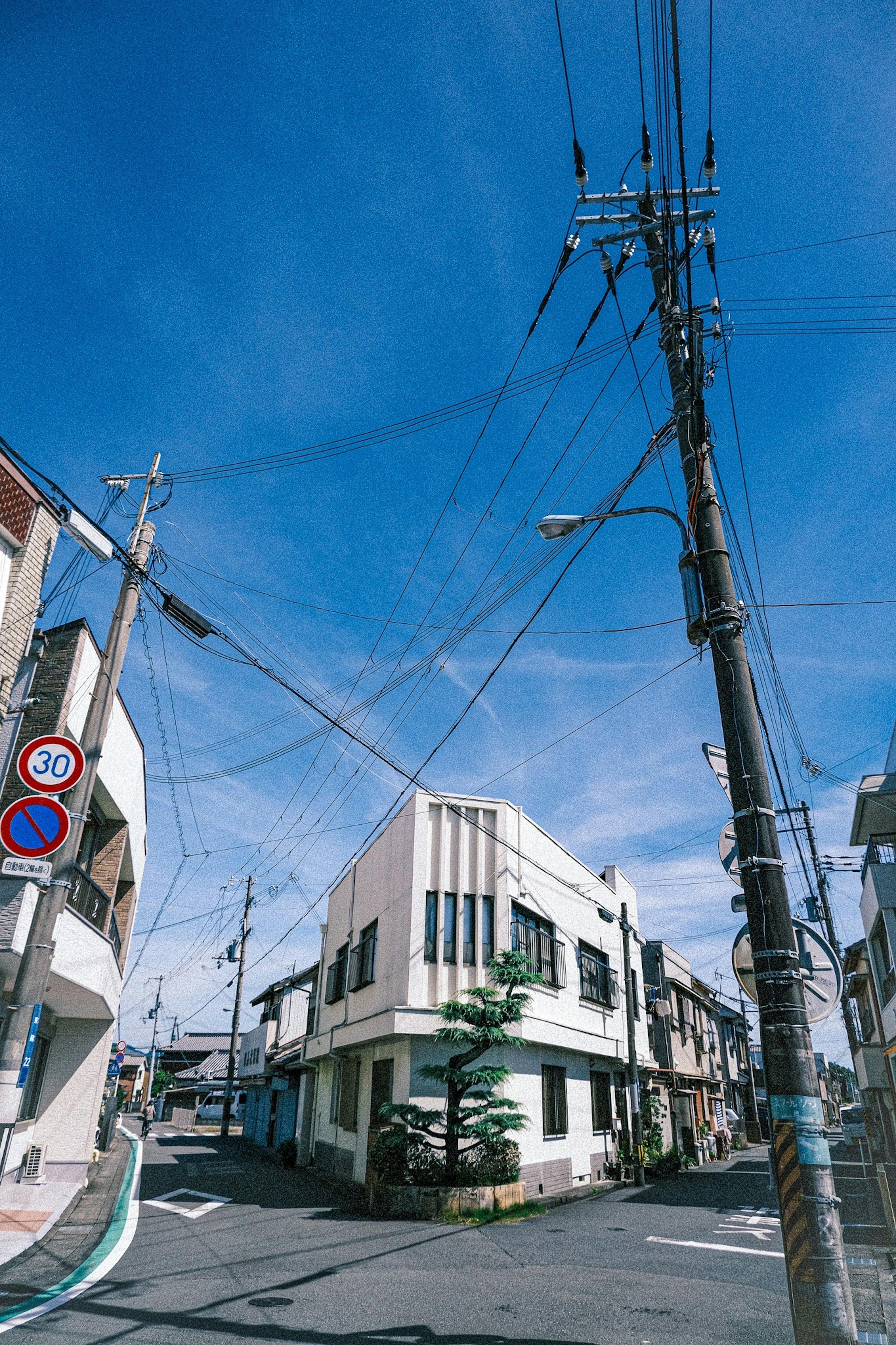 Vue de rue à un carrefour avec un bâtiment vintage et des poteaux électriques sous un ciel bleu