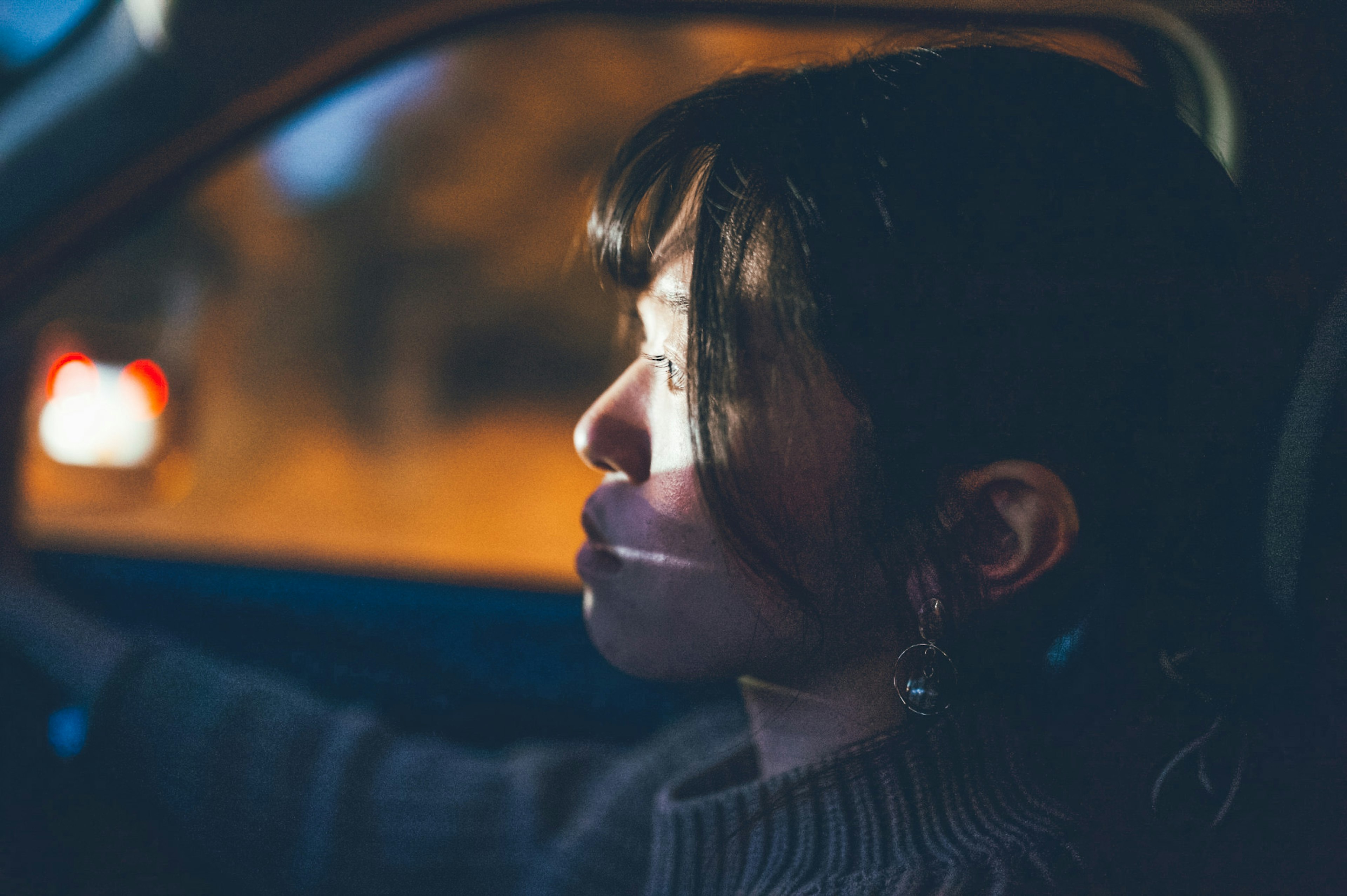 Perfil lateral de una mujer conduciendo en un coche con luz iluminando su rostro