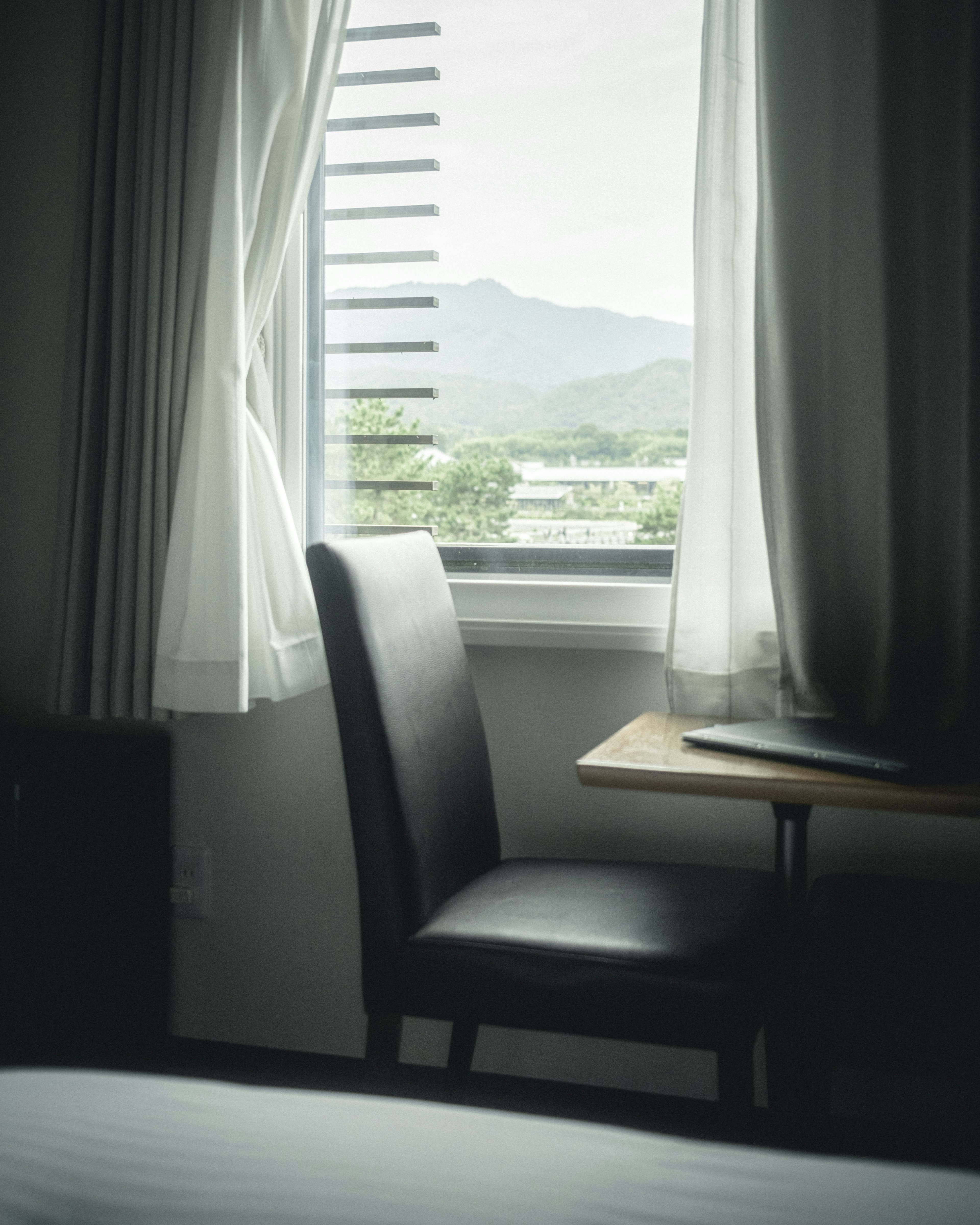 Chambre calme avec une chaise et une table près de la fenêtre