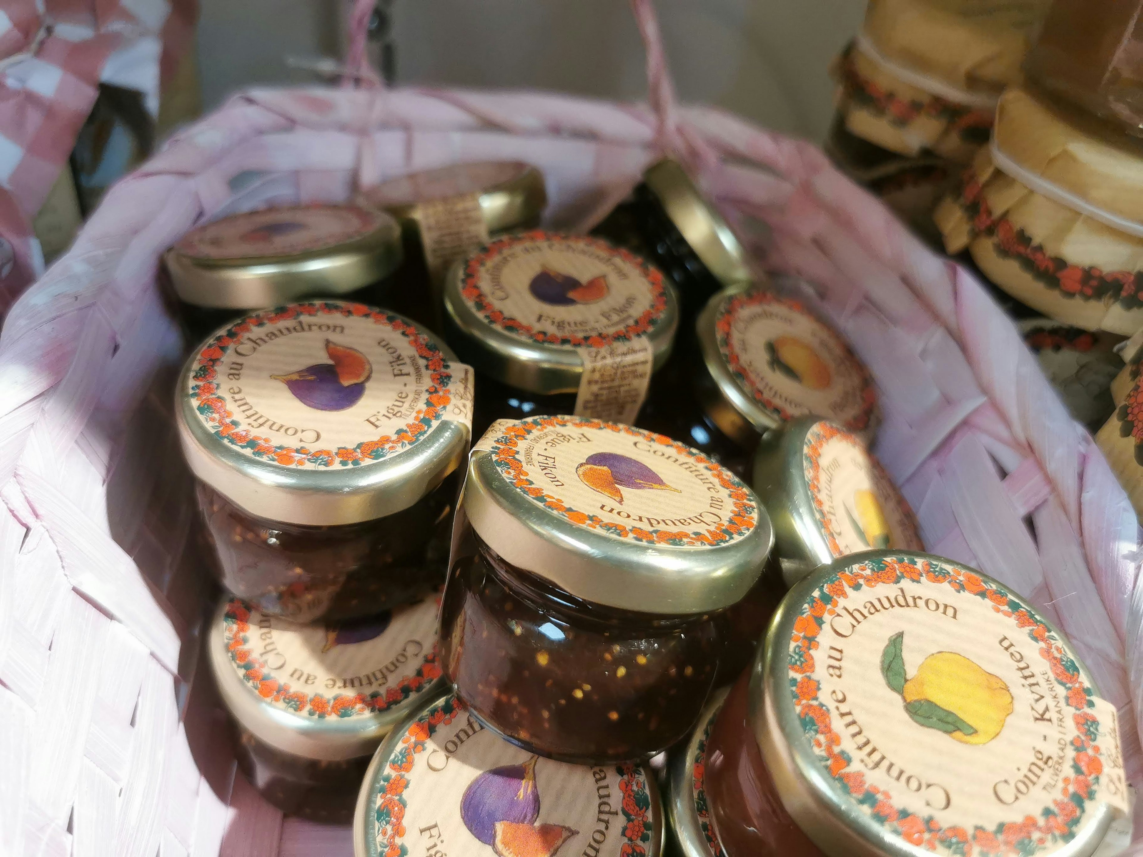 Colorful jars of jam in a pink basket