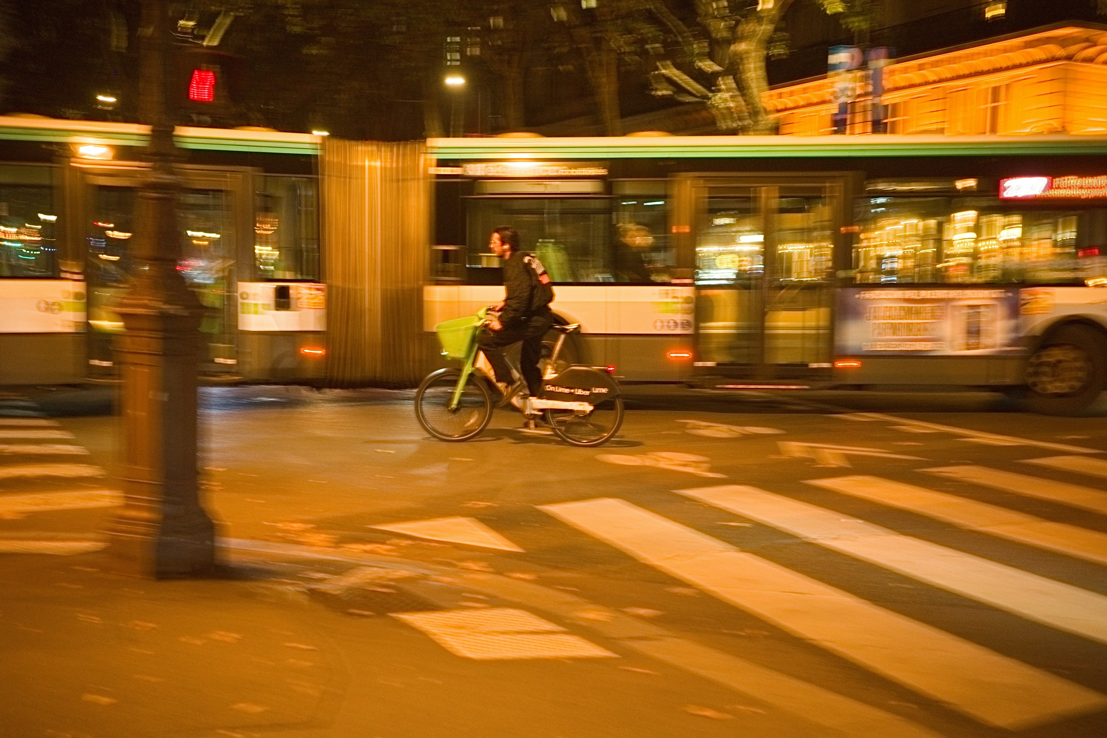 Una persona montando en bicicleta en un entorno urbano con un autobús en movimiento