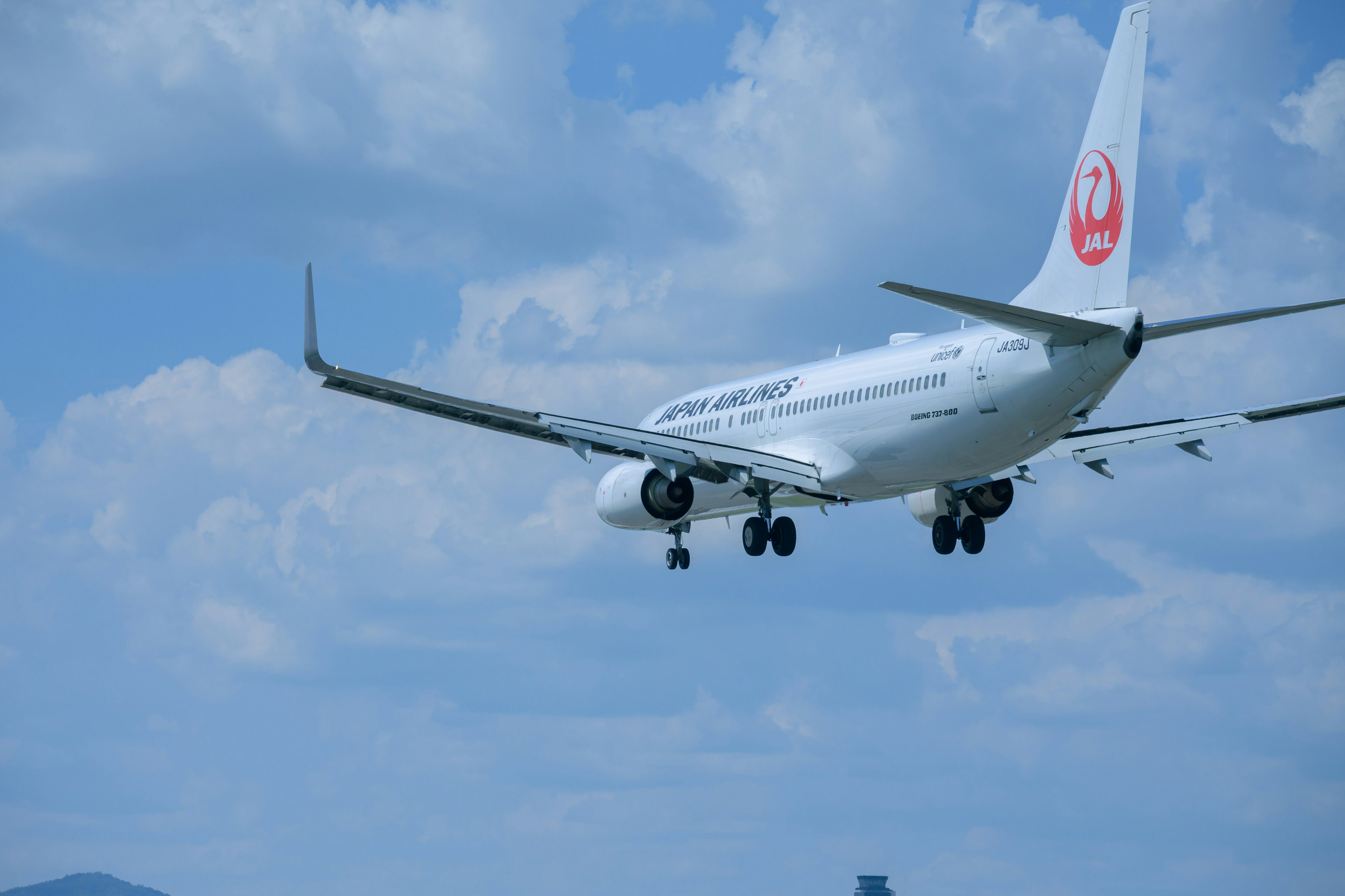 Weißes Flugzeug fliegt im blauen Himmel mit weißen Wolken