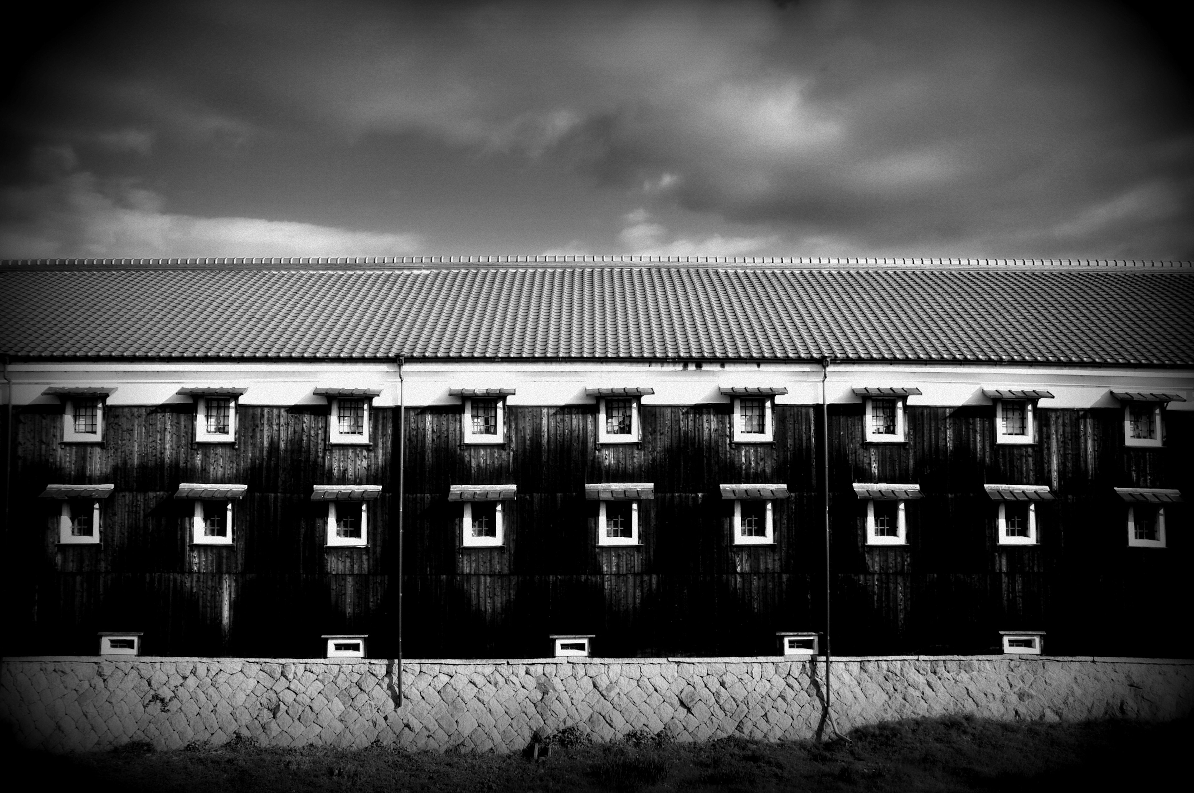 Black and white exterior of a building featuring a row of windows and a roof