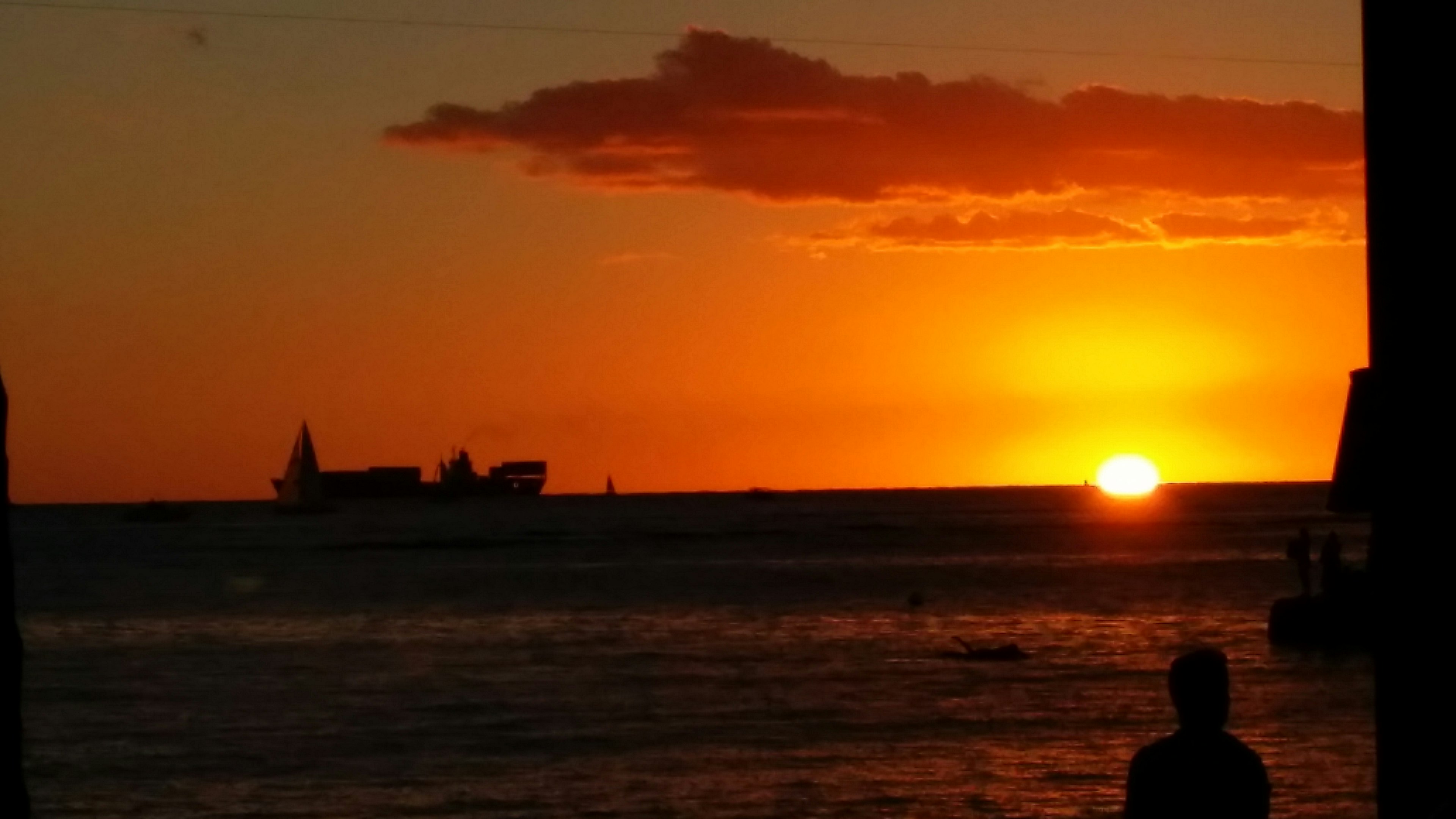 Tramonto arancione sull'oceano con una nave in silhouette