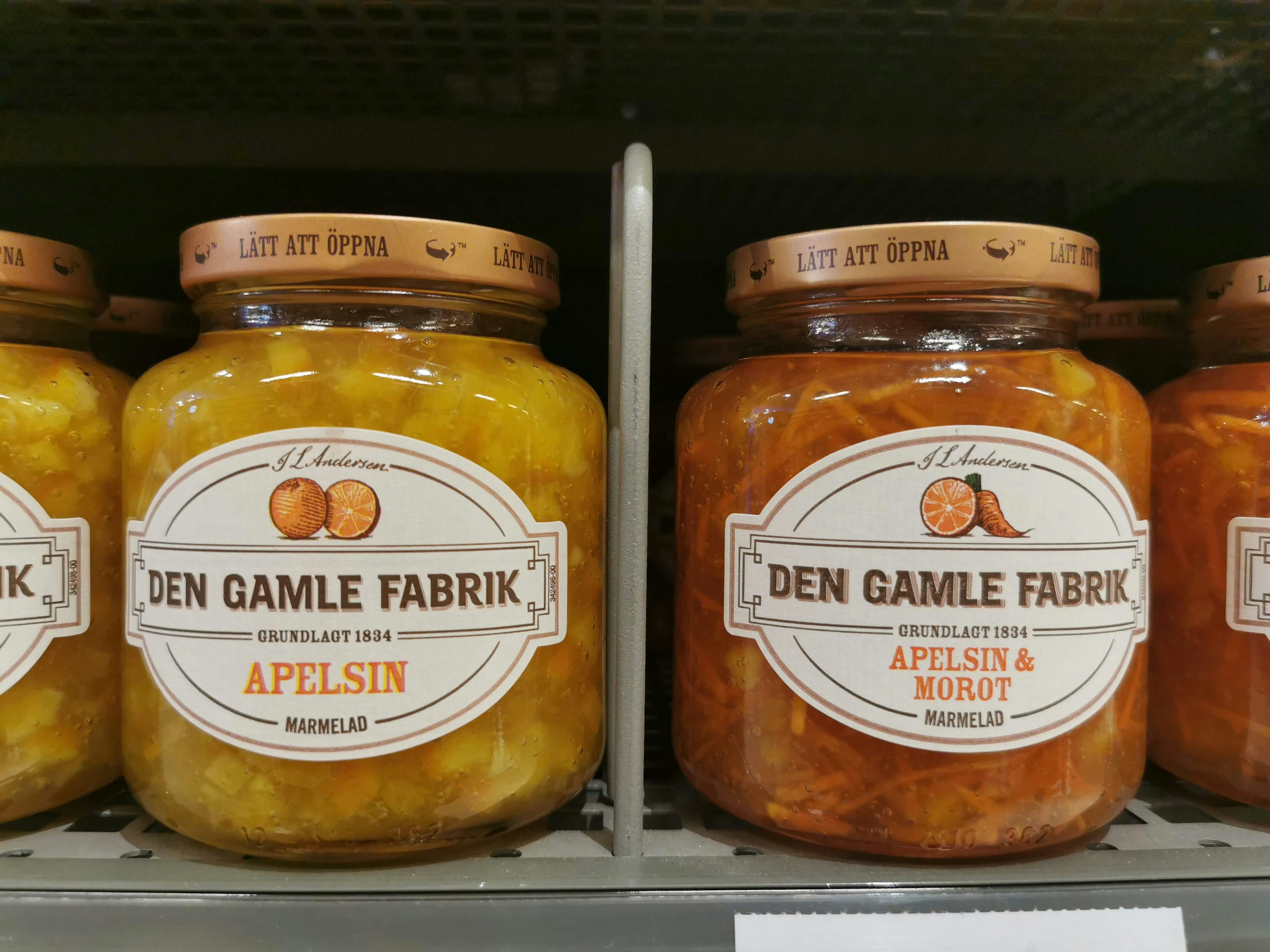 Jars of orange jam and apricot jam displayed on a shelf