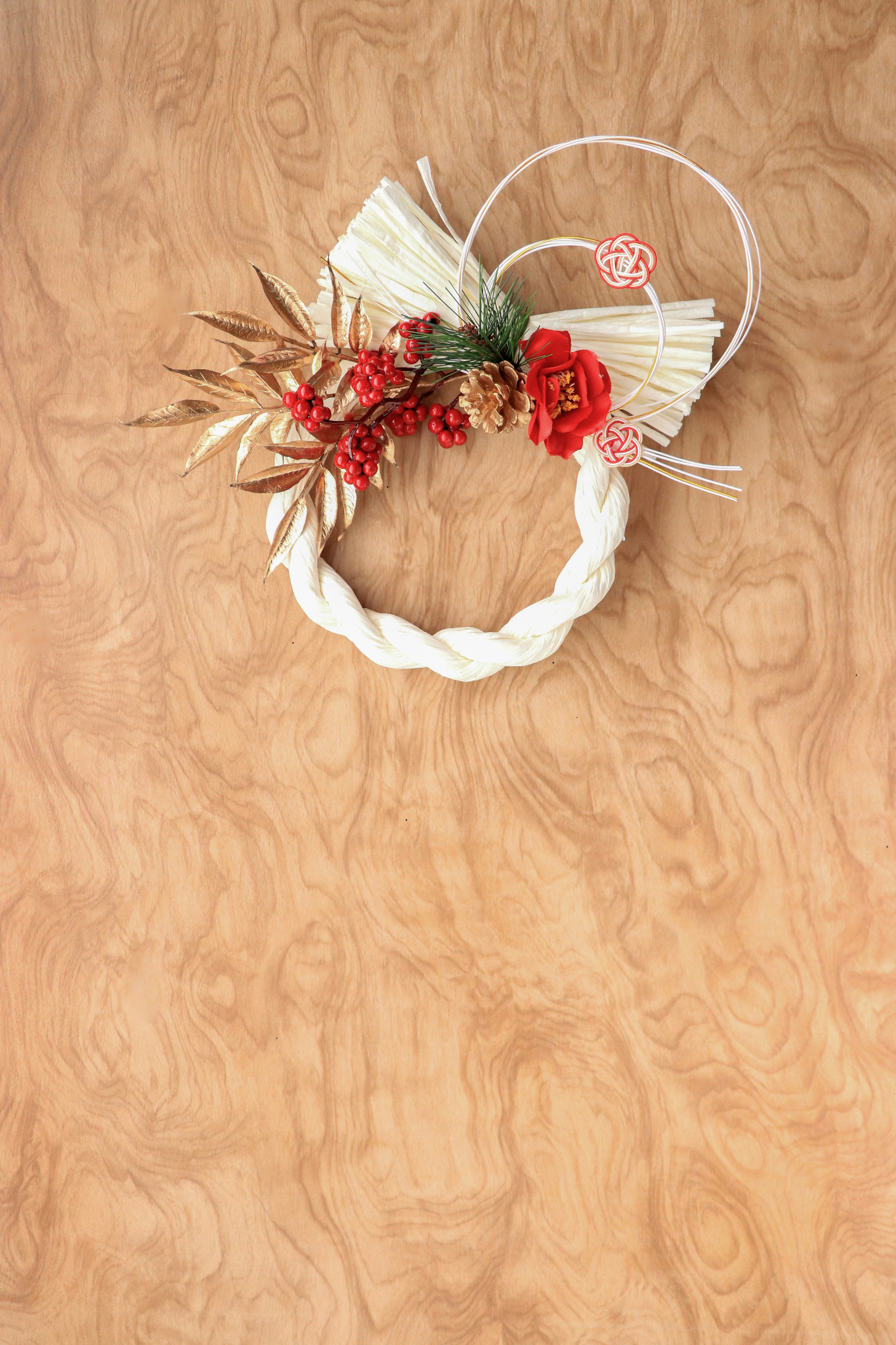 Decorative white braided wreath with red flowers and golden leaves