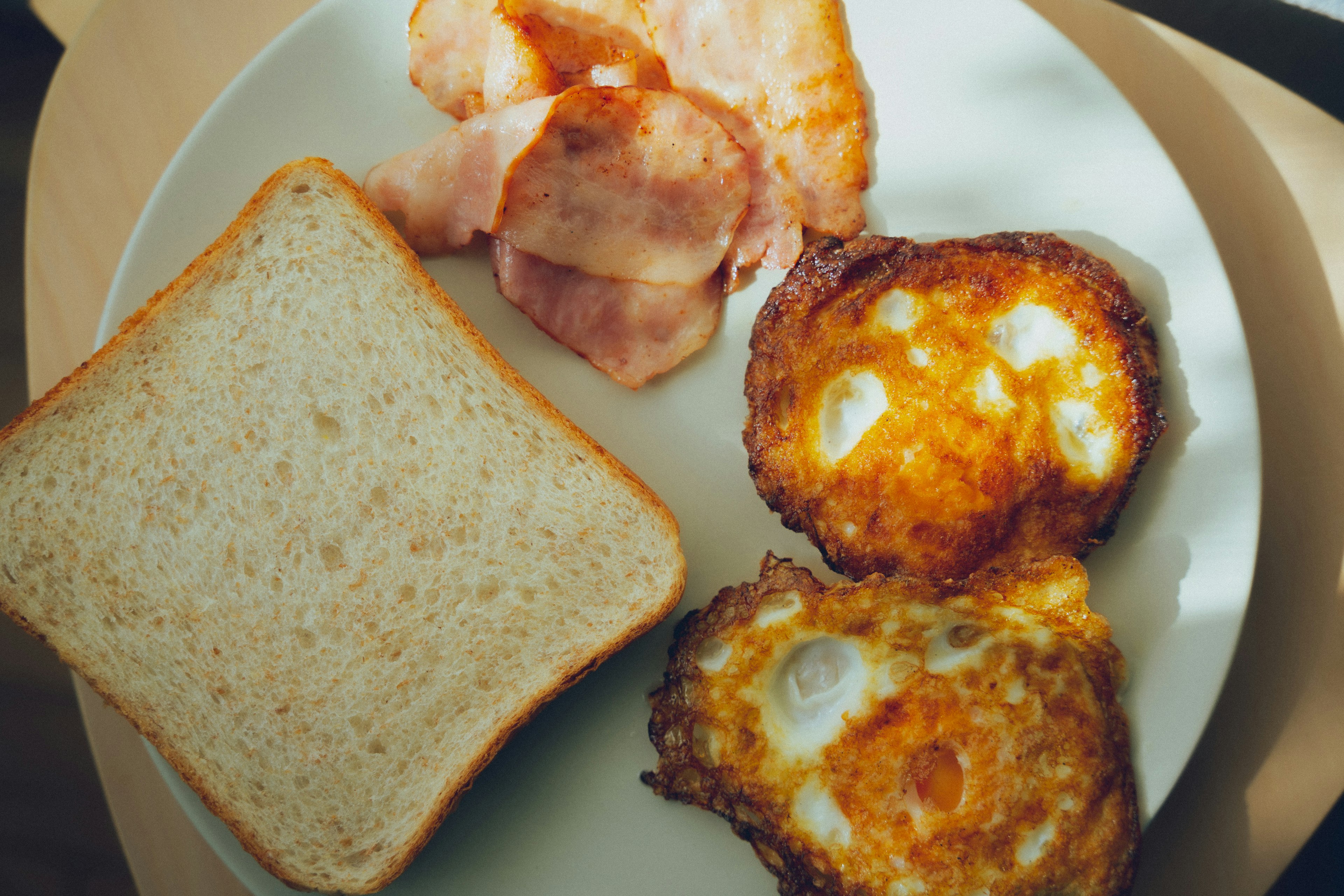 トースト、目玉焼き、ベーコンが盛り付けられた朝食プレート