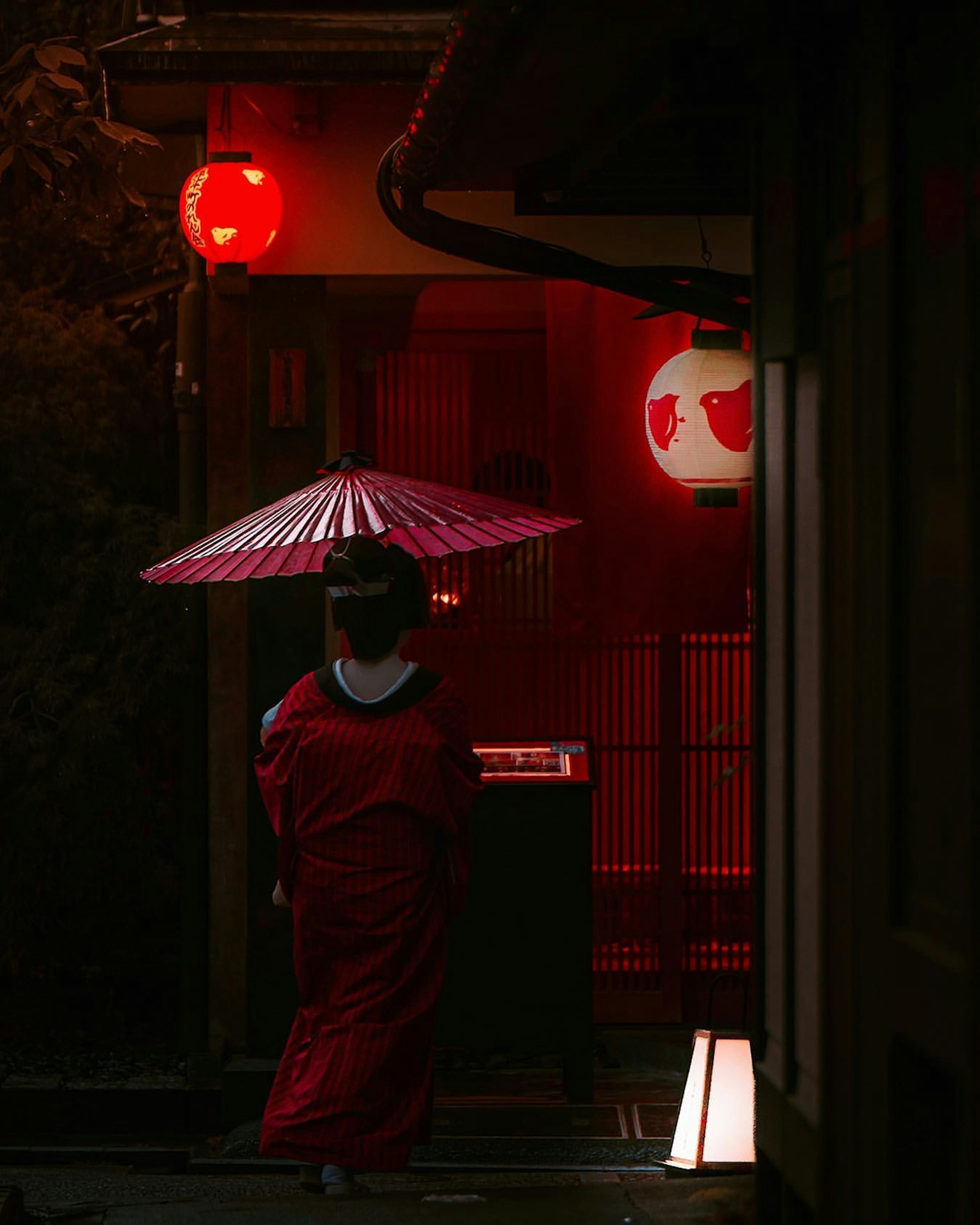 Mujer en kimono rojo caminando bajo linternas rojas