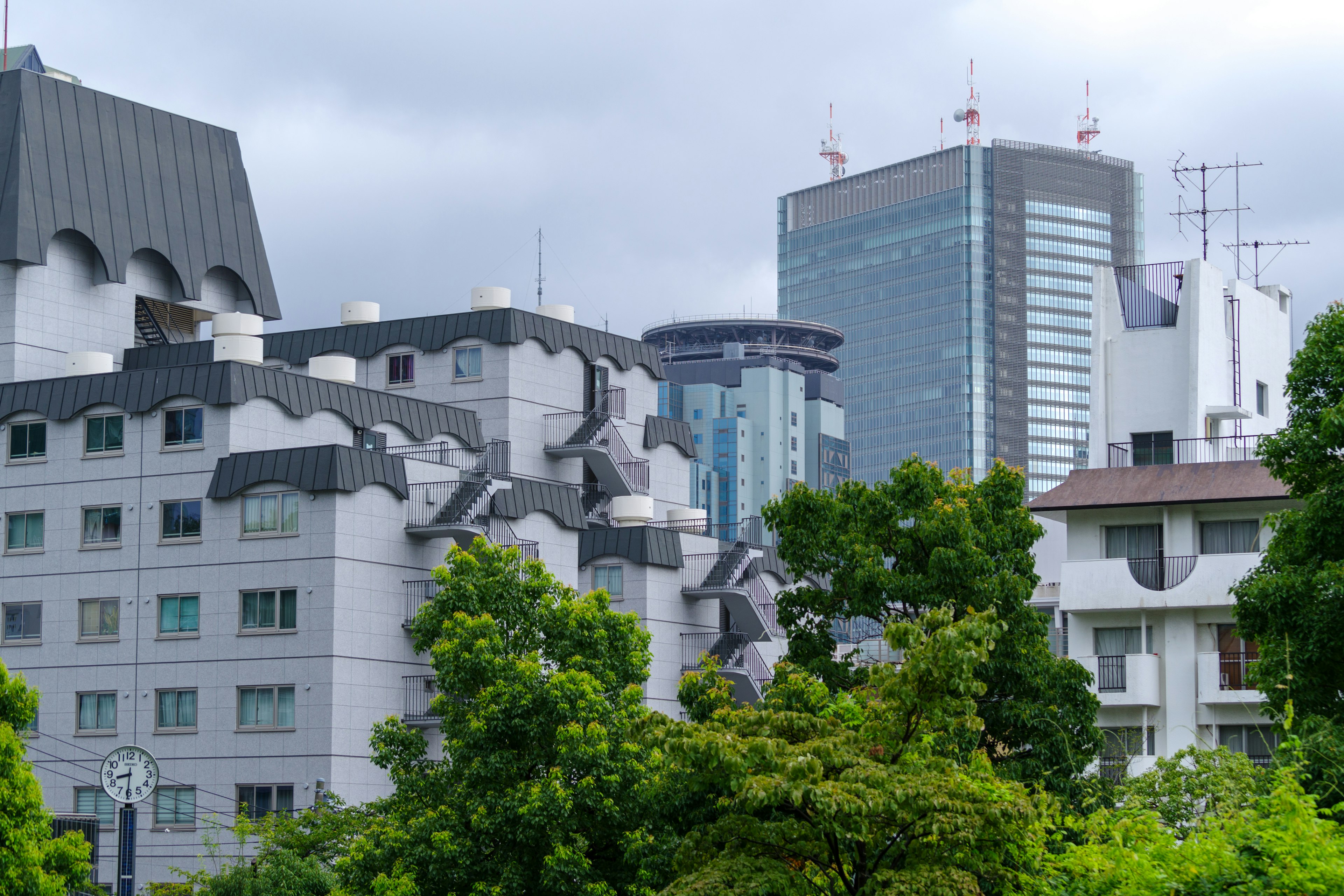 Moderne Wolkenkratzer und verschiedene Architekturstile zwischen üppigen grünen Bäumen sichtbar