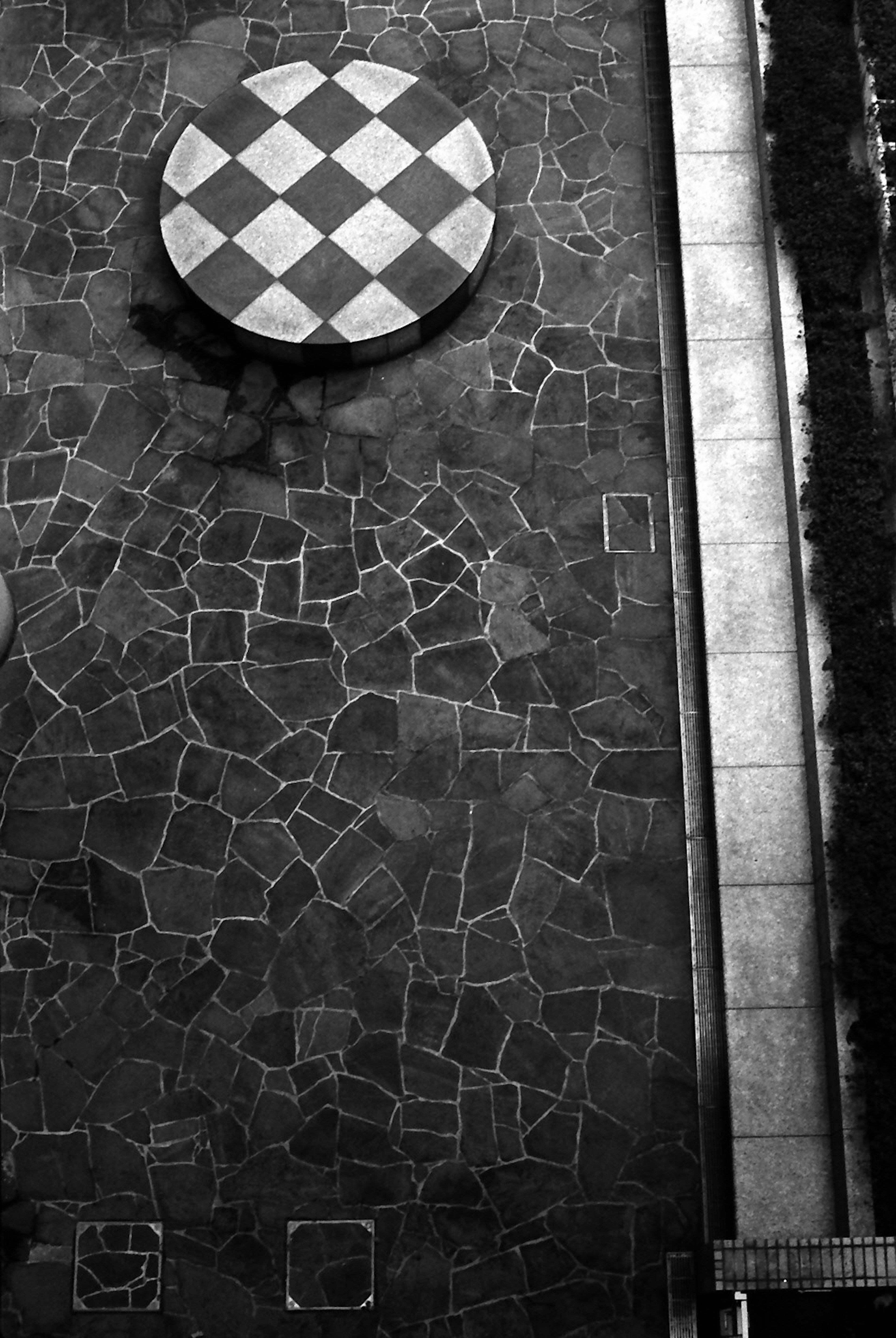 Outdoor scene featuring a black and white checkered table and stone pavement pattern