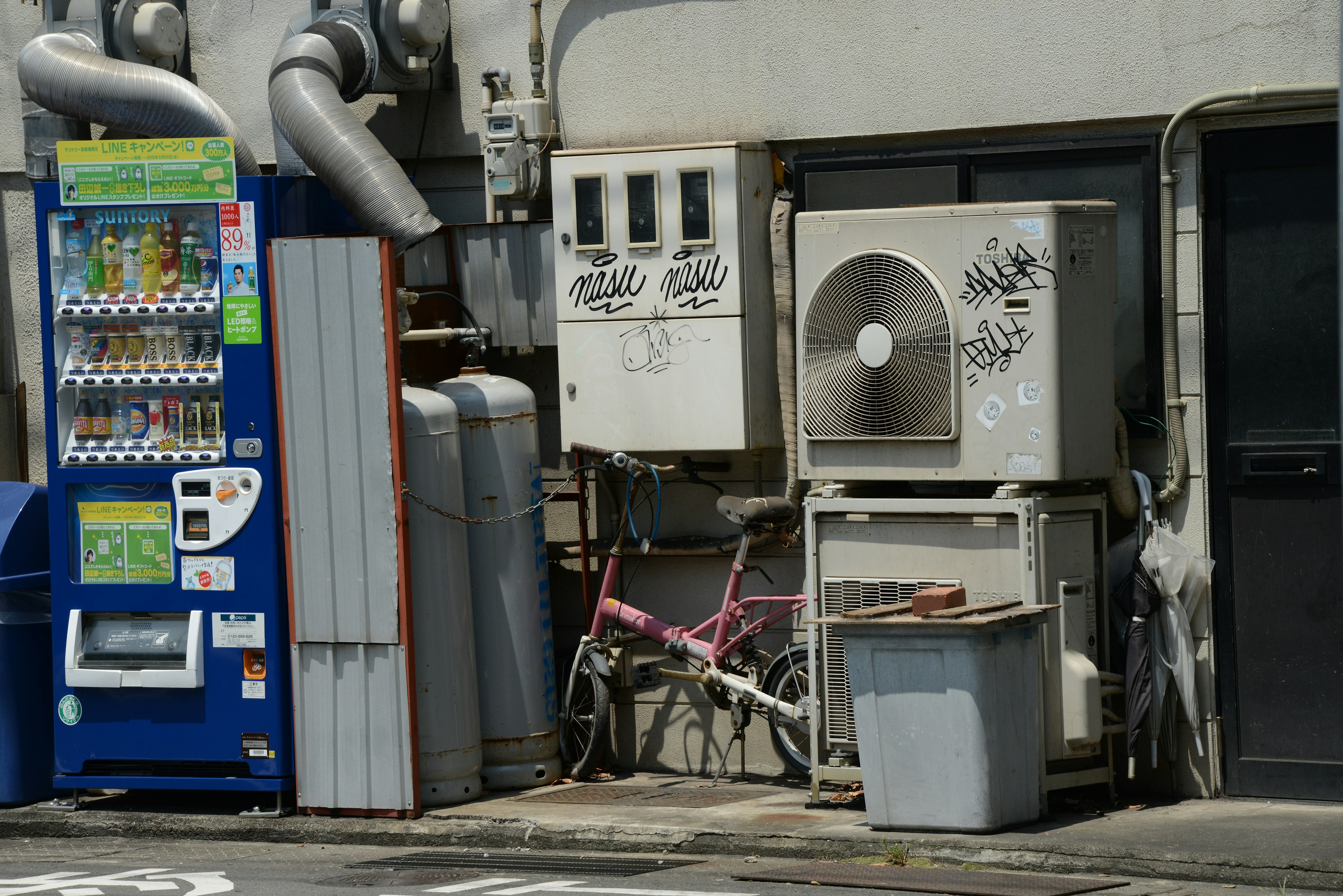 Street corner scene featuring a vending machine and an air conditioning unit