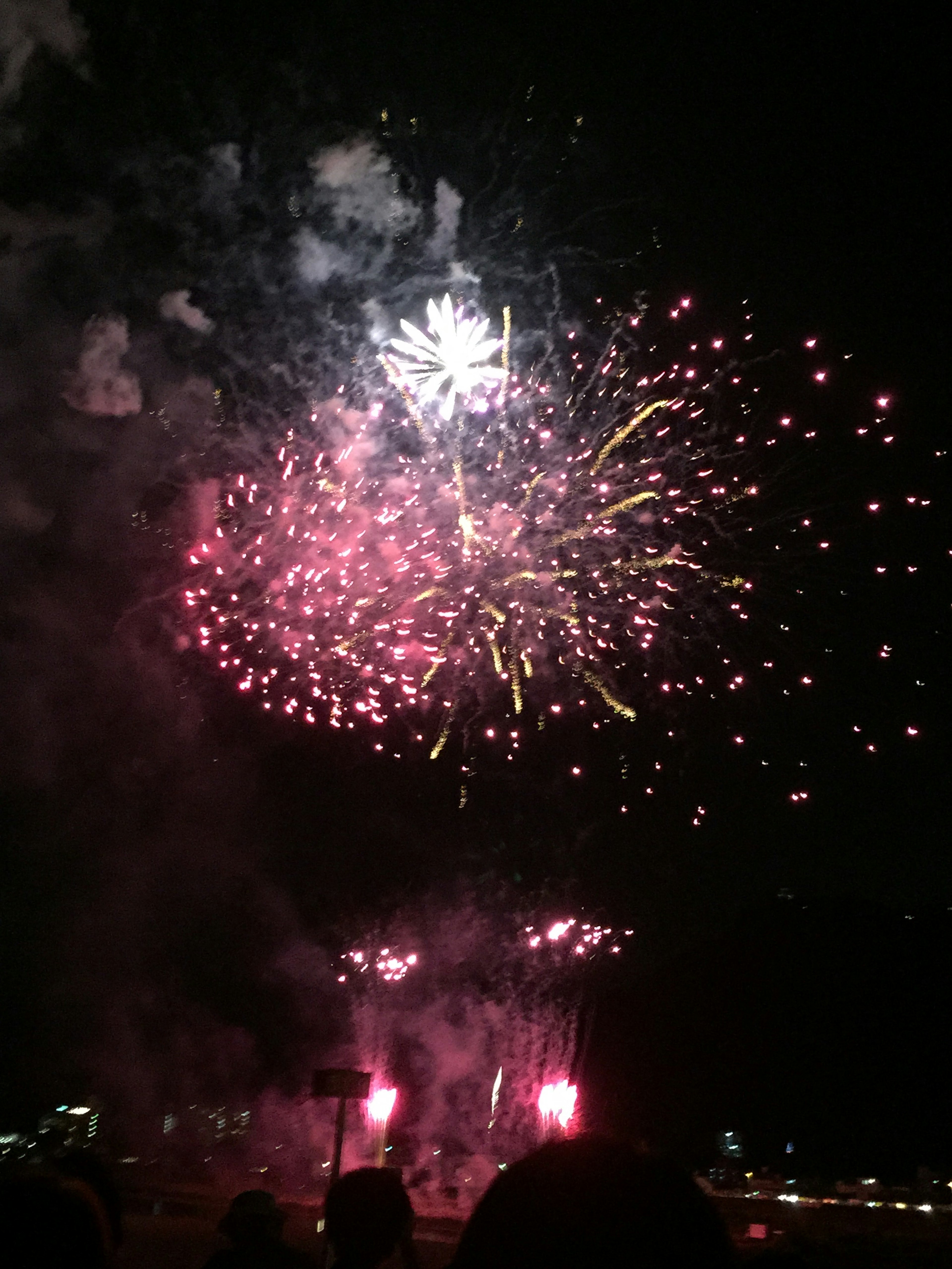 Vibrant fireworks display in the night sky featuring red and white sparks