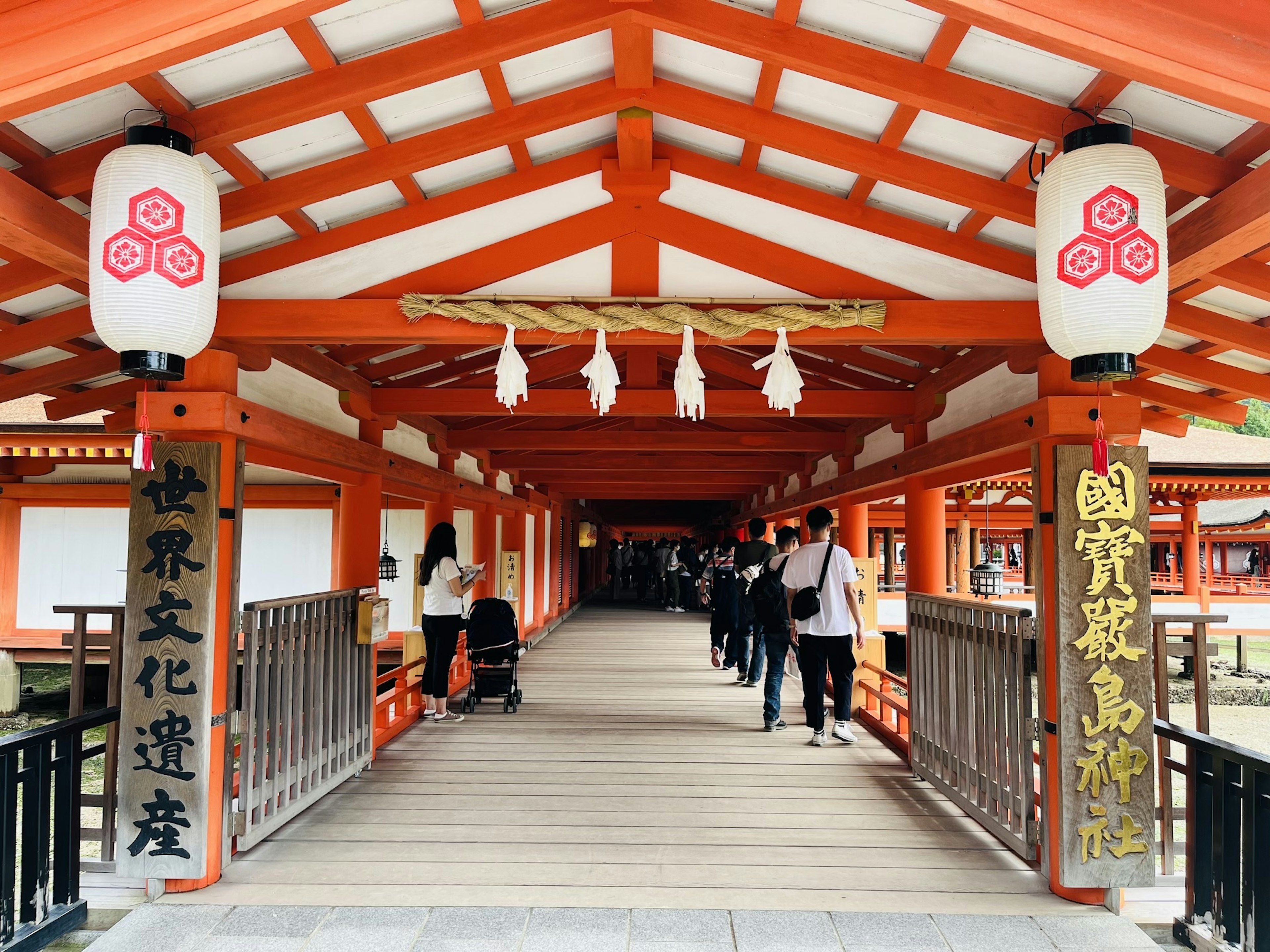 A scenic view of people walking on a red-roofed bridge adorned with lanterns