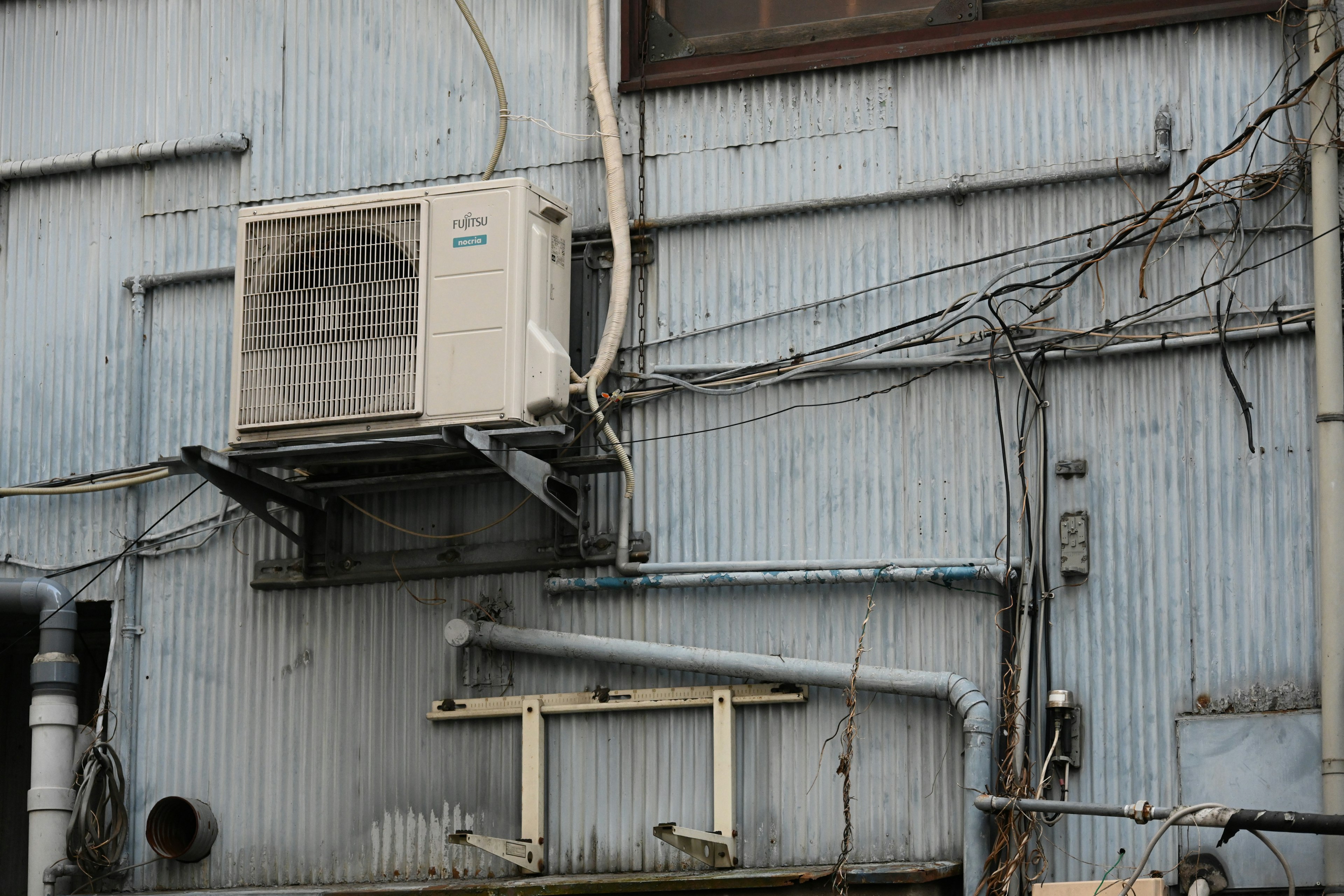 Air conditioning unit mounted on a blue wall with visible piping details