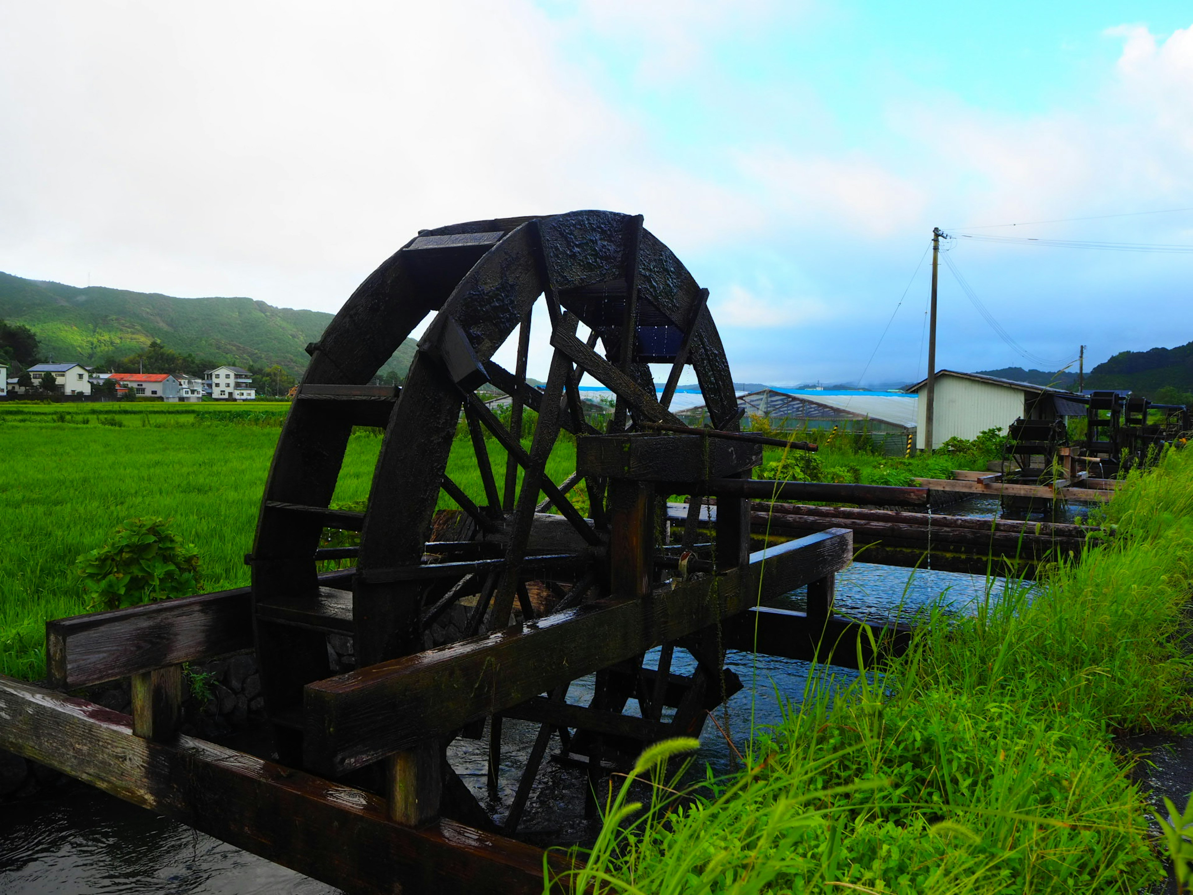 緑の田園風景にある水車と水の流れ