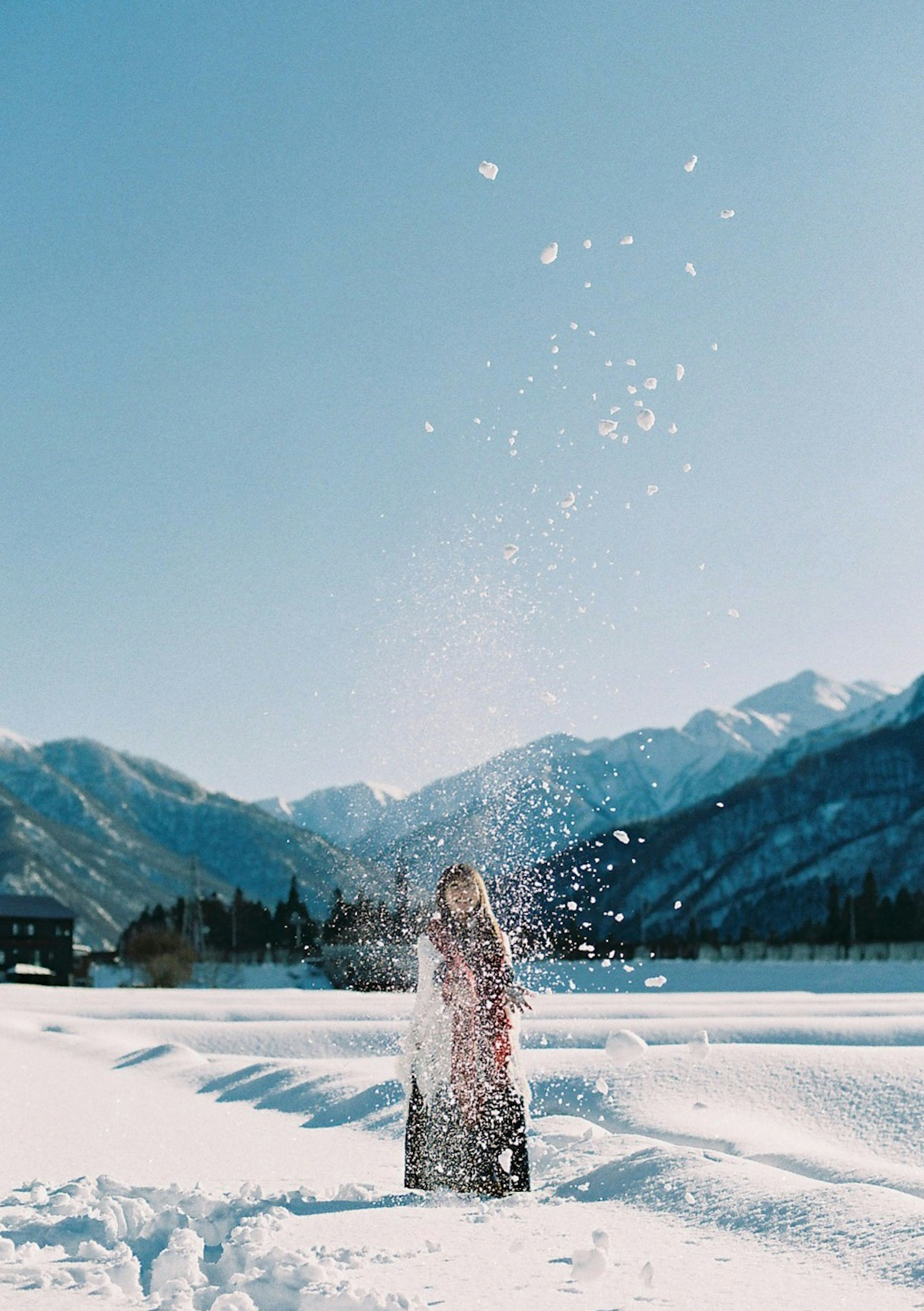 Person spielt im Schnee mit Schneeflocken in der Luft