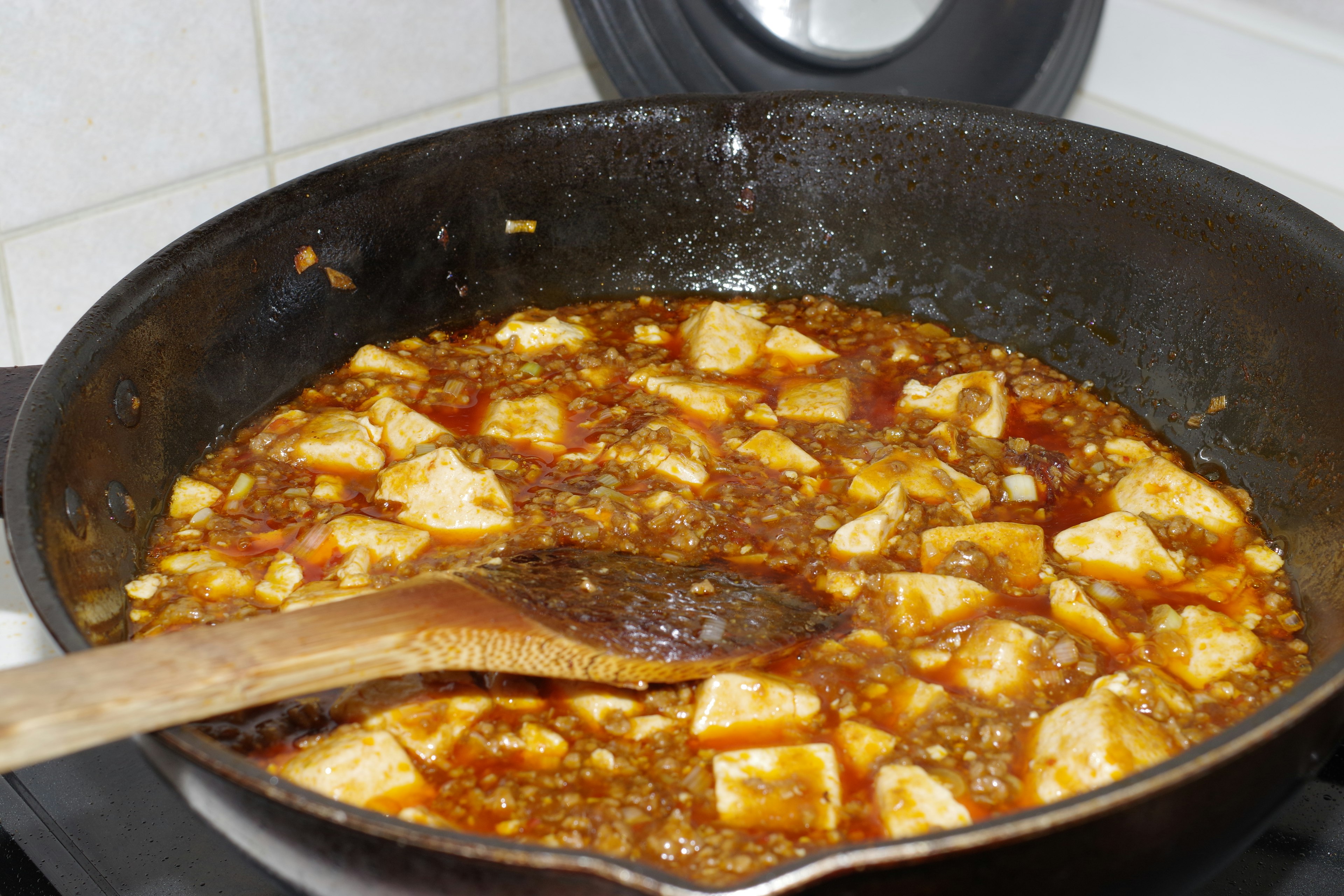 Tofu in a savory sauce cooking in a frying pan