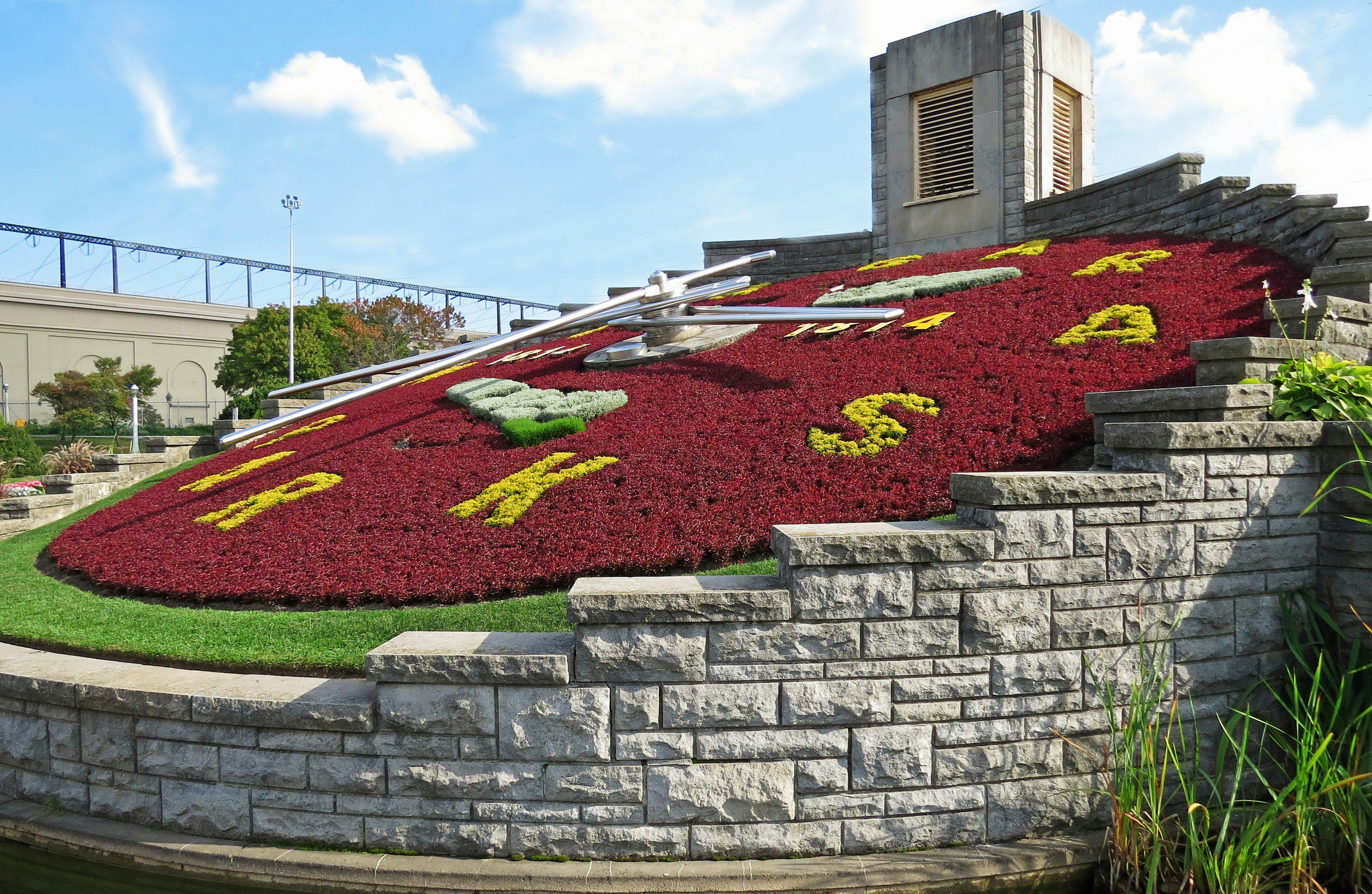 Large flower clock garden featuring colorful floral designs and stone landscaping