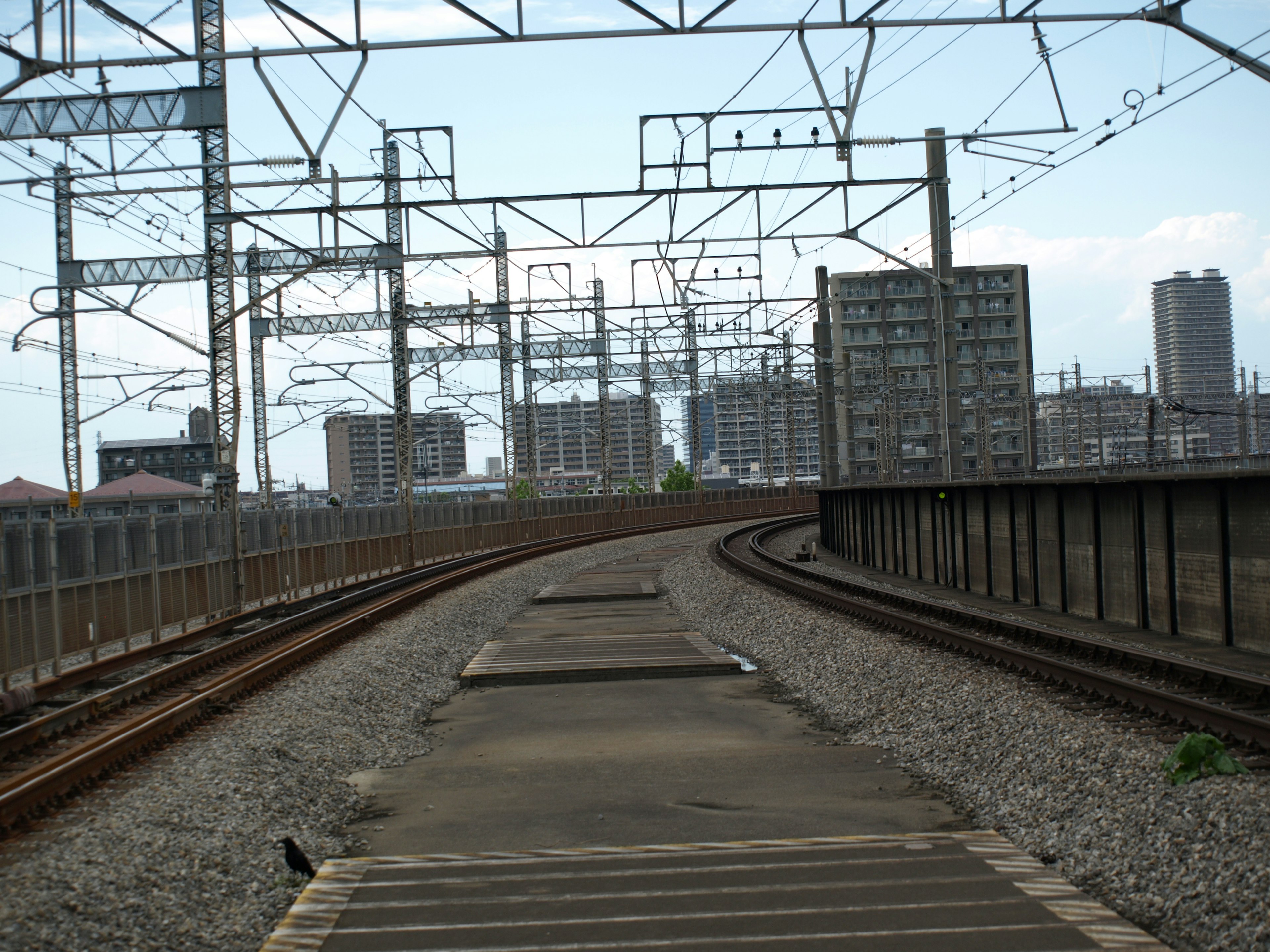 รางรถไฟที่โค้งงอพร้อมอาคารสูงรอบๆ