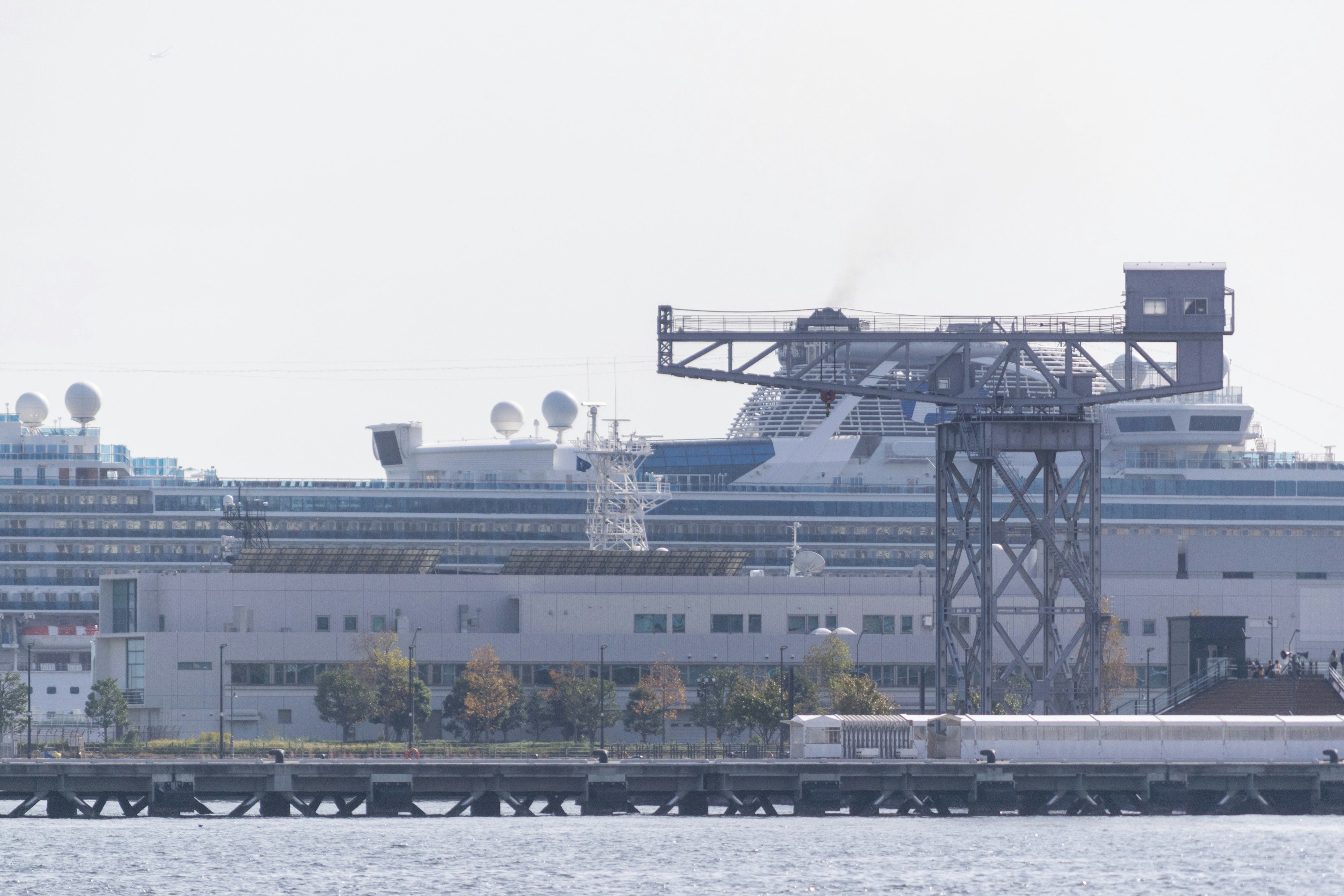 Image of a cruise ship docked at a port with a large structure