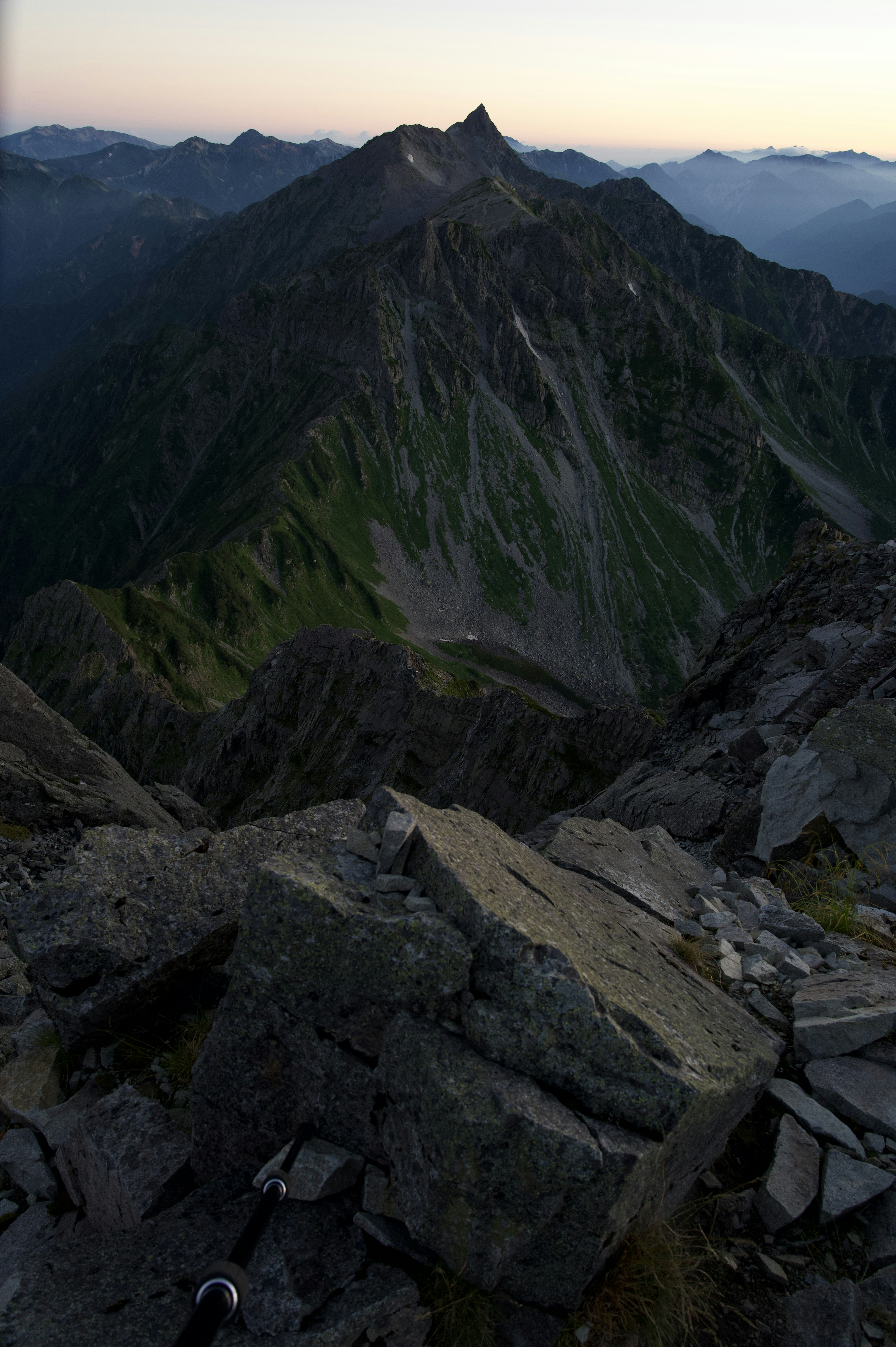 View from a mountain summit featuring rocky terrain and green slopes