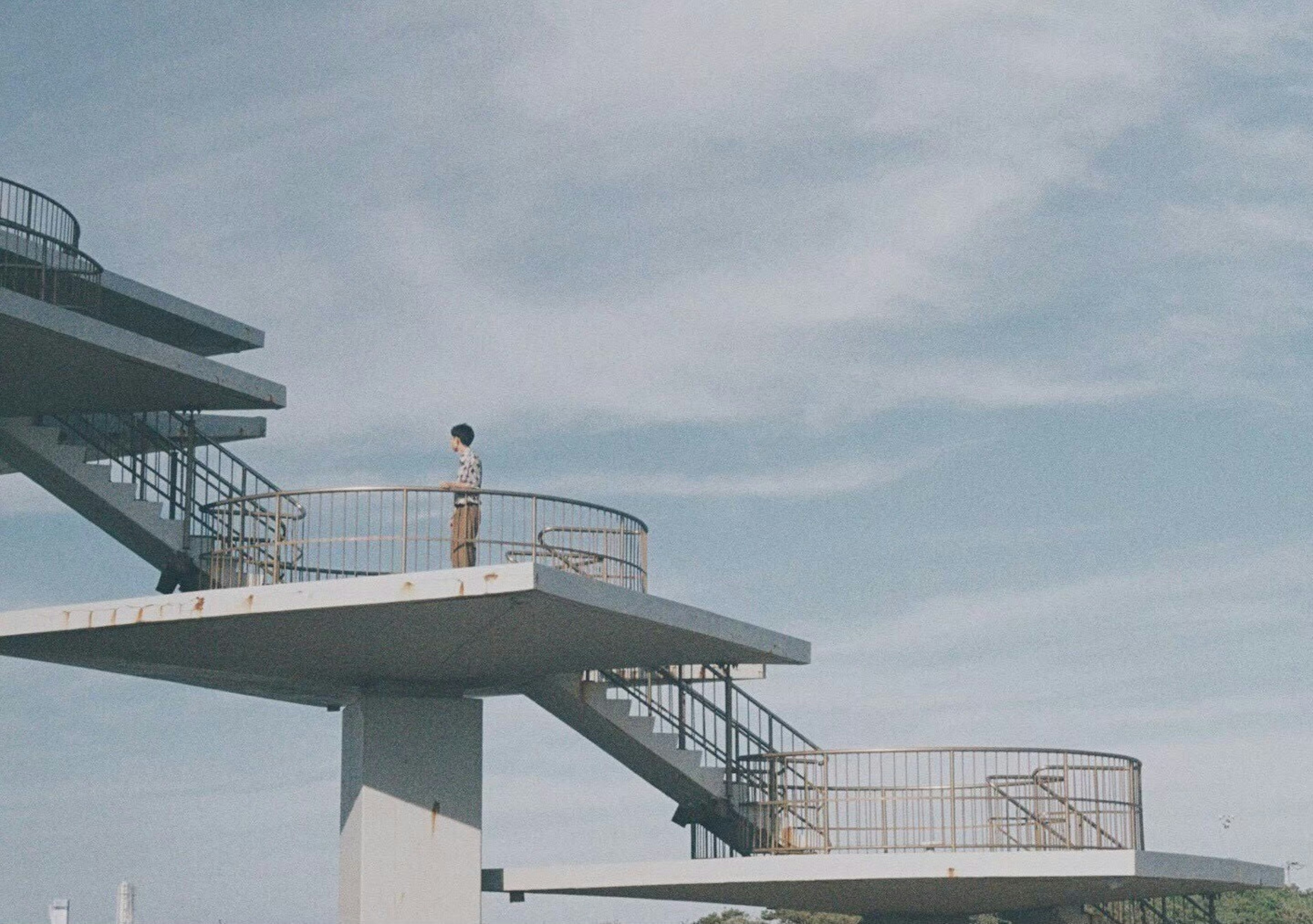 Une plateforme de plongeon haute sous un ciel bleu avec une personne debout dessus