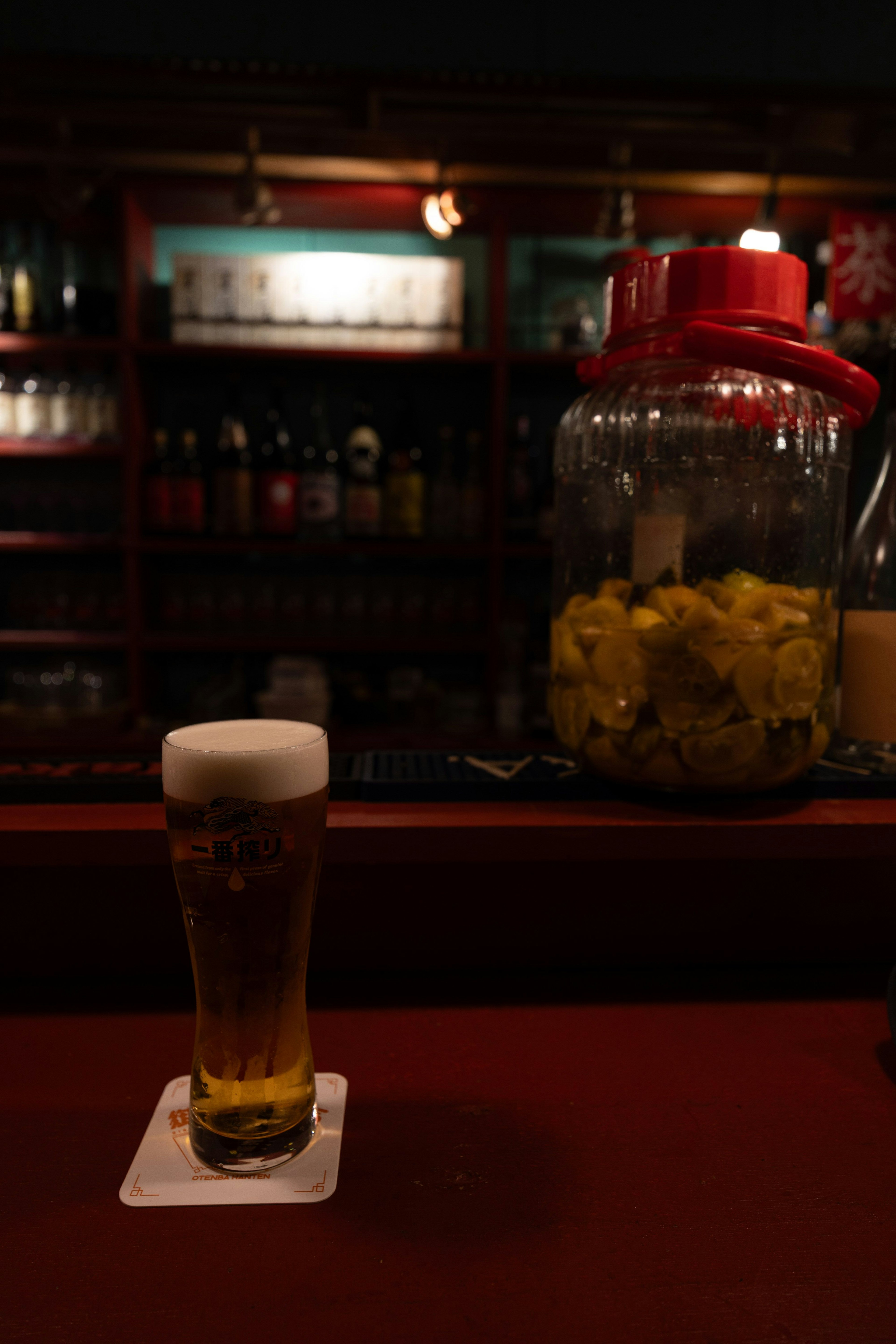 Ein Glas Bier und ein Glas mit Früchten auf einer Bar-Theke