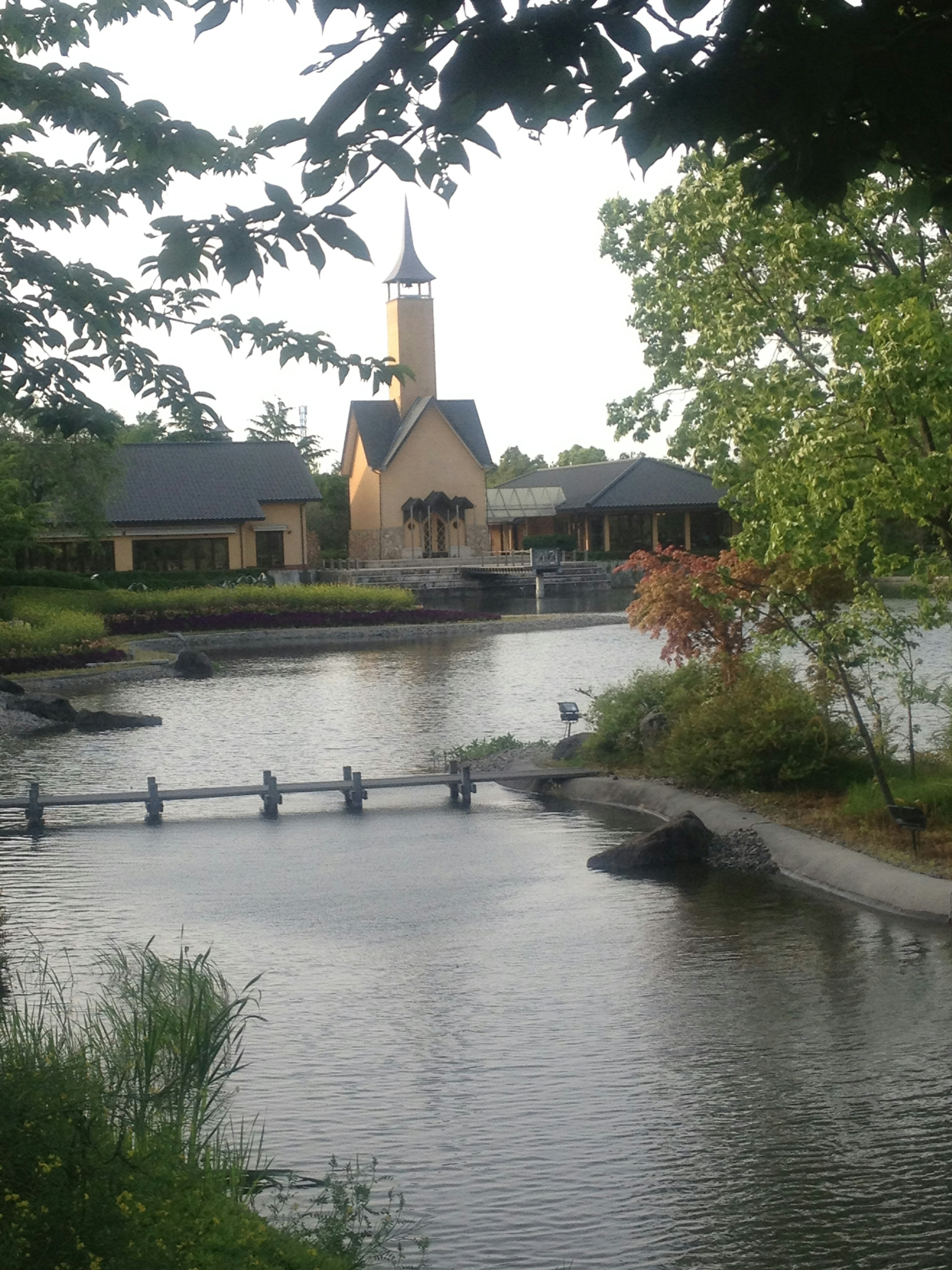 Vista escénica de una torre de iglesia junto a un lago tranquilo con vegetación exuberante