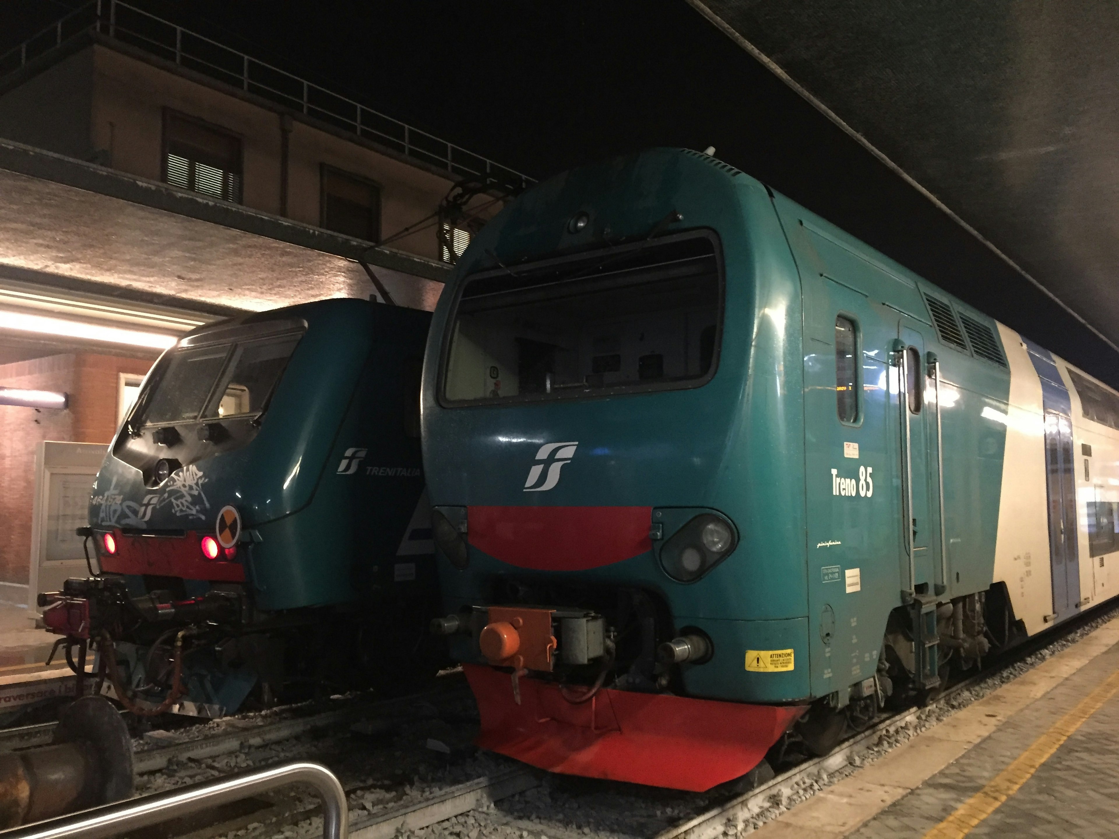 Two blue trains parked at a station at night