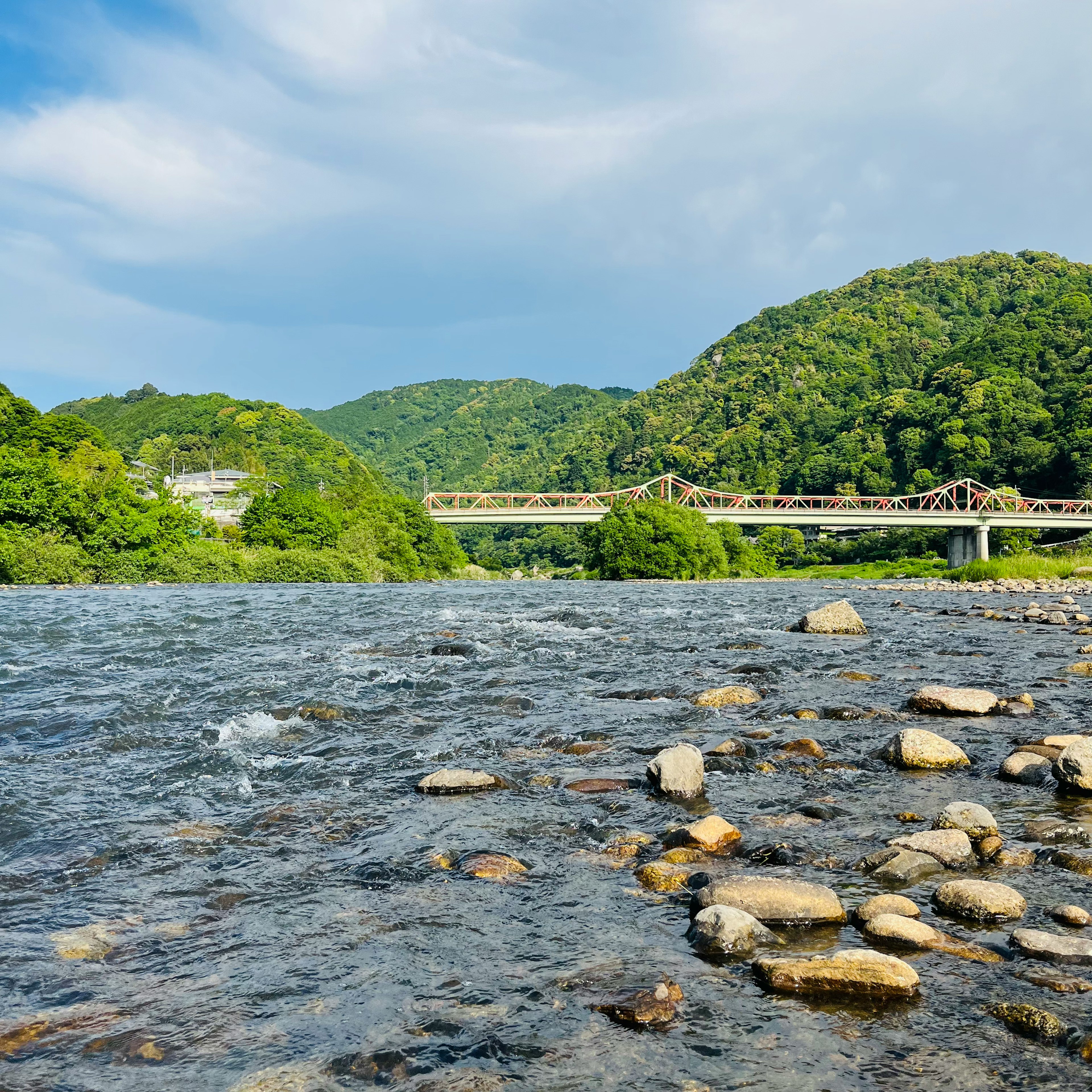 Scenic view of a river with a bridge surrounded by lush green hills